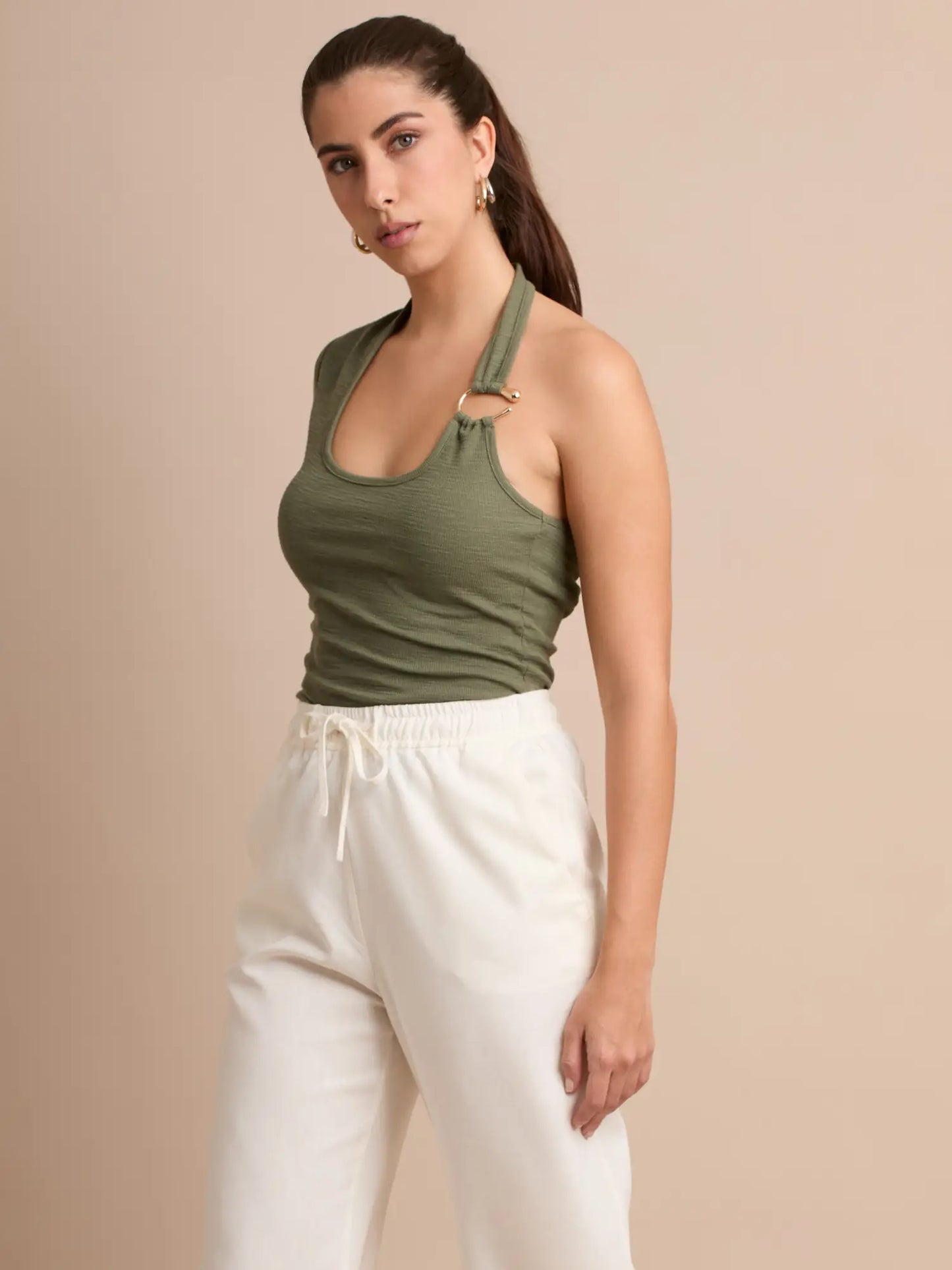 Una pieza fresca y juvenil con un diseño halter irregular que aporta dinamismo. El aro dorado en el tirante añade un detalle elegante que transforma un básico en un must-have de temporada.