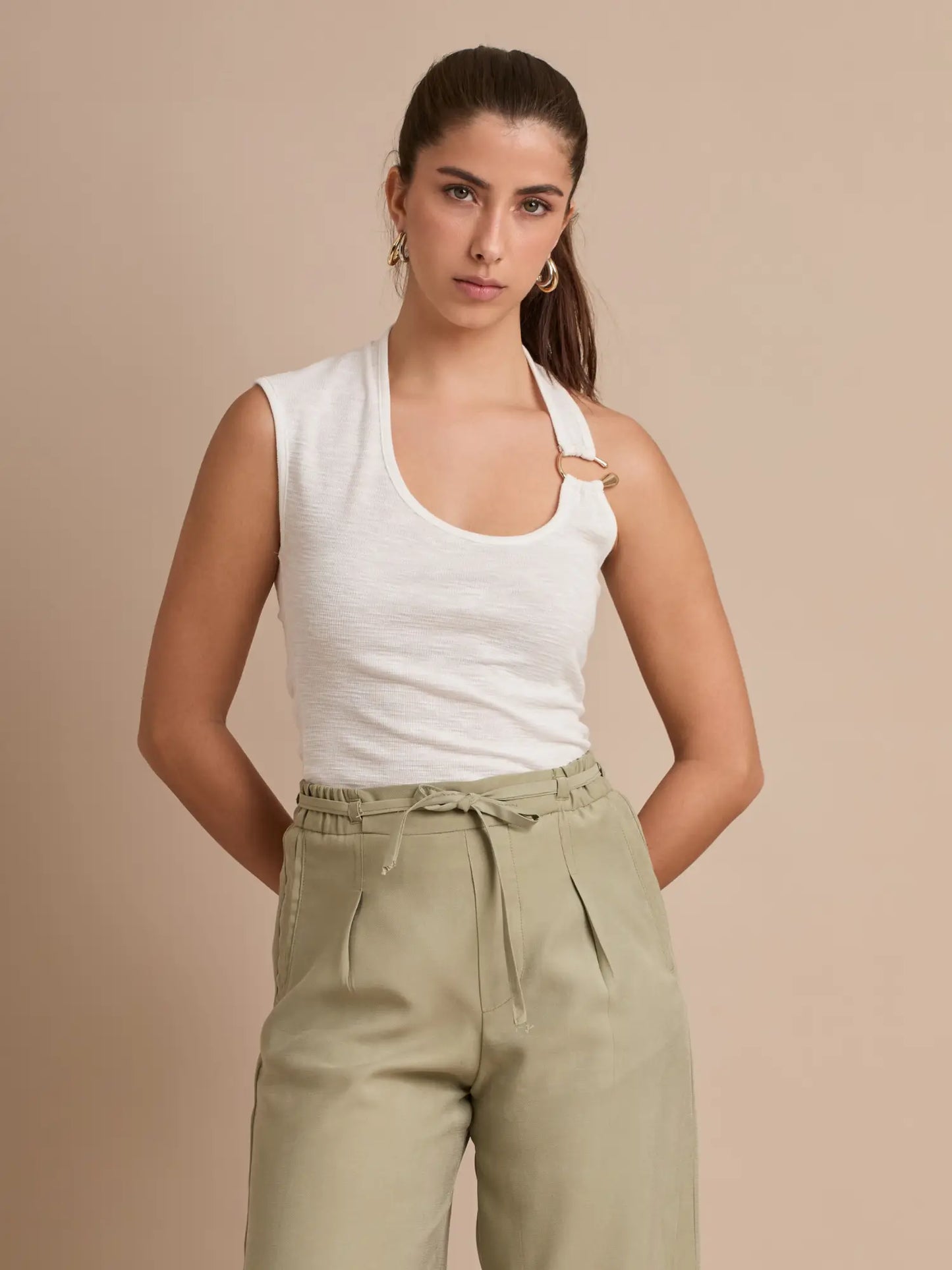 Un diseño que transforma lo básico en elegante: blusa blanca con tirante halter asimétrico y aro metálico. Su silueta favorecedora la convierte en un esencial de temporada.