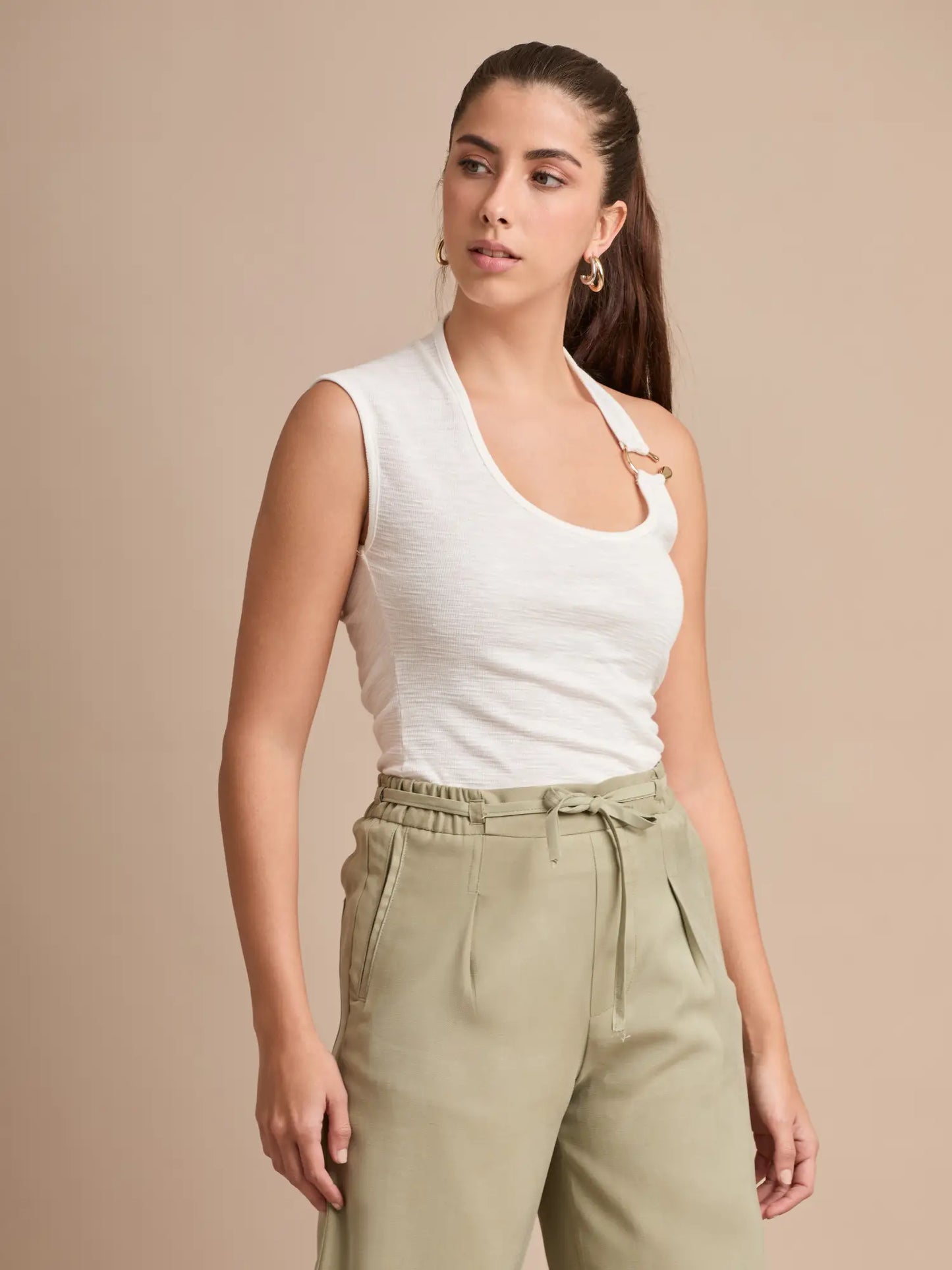 Un top ligero y elegante con diseño halter irregular y doble aro dorado en el tirante. Su color blanco lo convierte en un básico imprescindible que combina con todo.