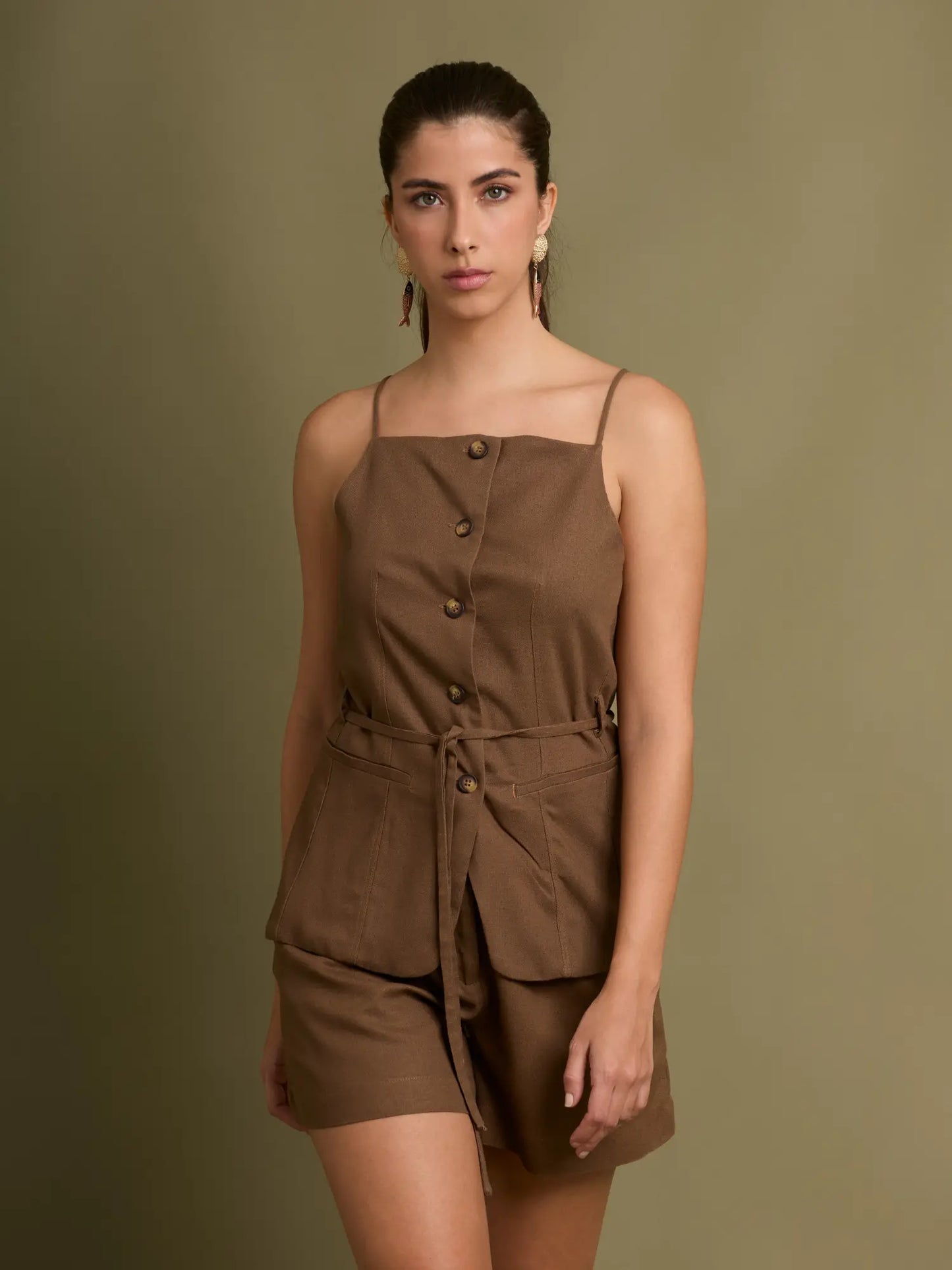 Este top estilo chaleco presenta botones frontales, tirantes finos y bolsillos de parche que aportan un look utilitario. Ideal para looks casuales con un toque sofisticado.