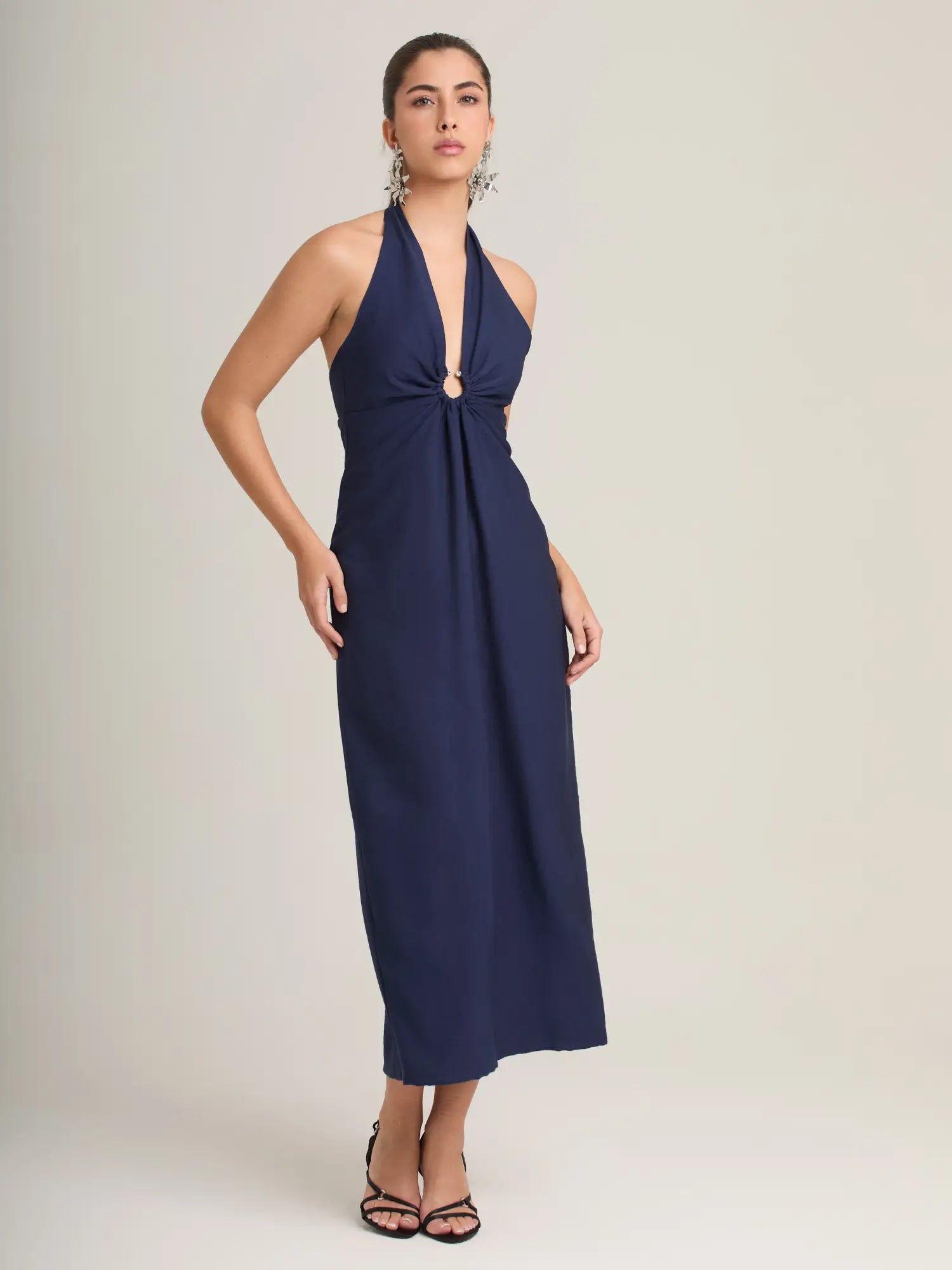 El vestido azul marino halter destaca por su elegancia atemporal, con una argolla central que estiliza y una falda midi que aporta sofisticación. Perfecto para eventos de noche y cenas especiales.