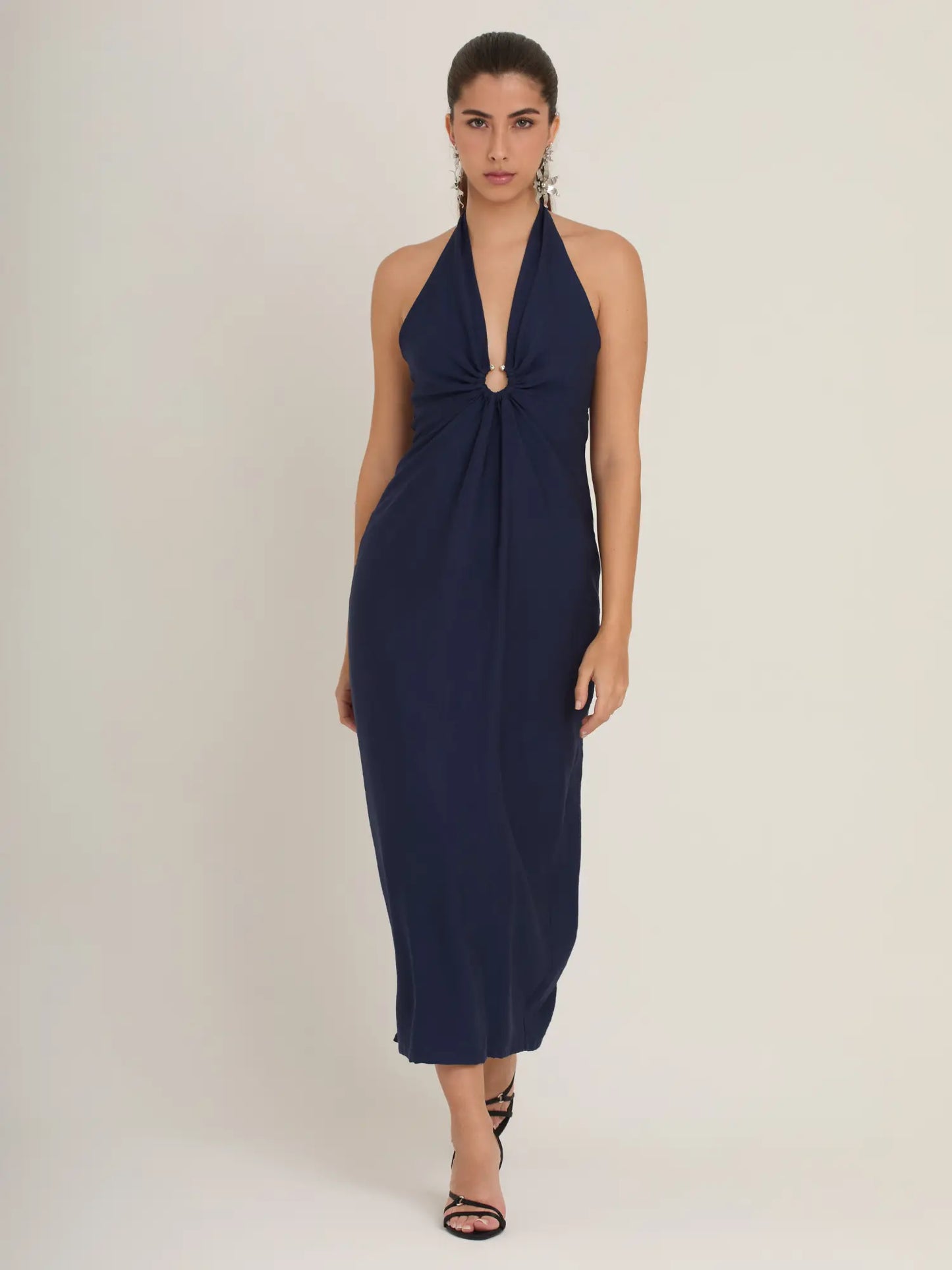 El vestido azul minimalista ofrece líneas limpias y una caída suave que estiliza. Su escote halter es favorecedor y perfecto para un look elegante sin esfuerzo.