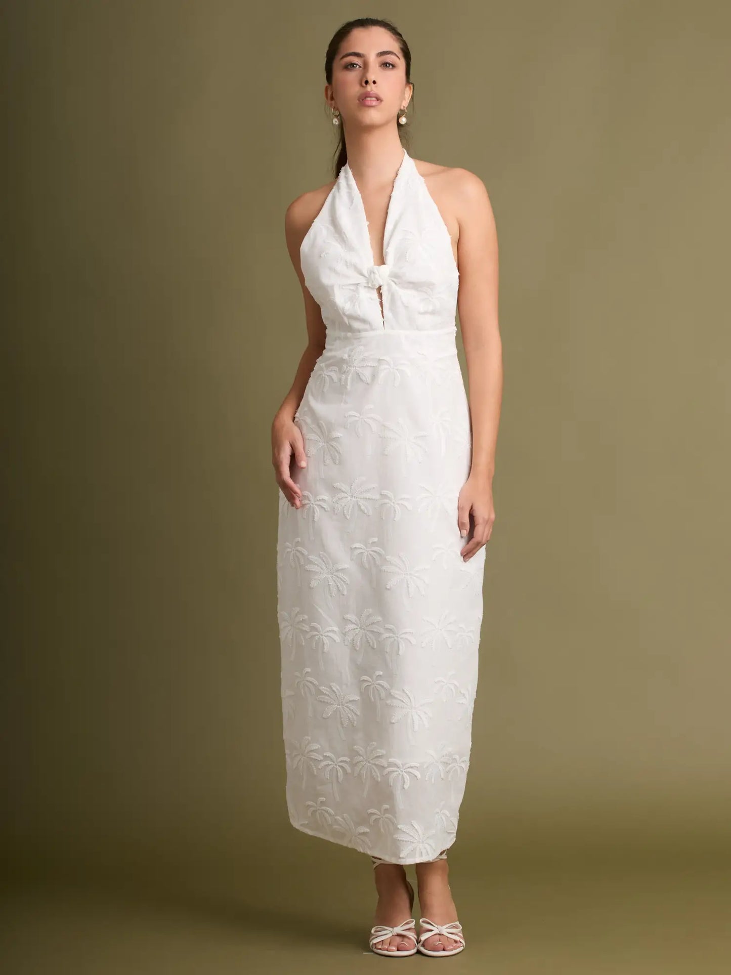 Este vestido destaca por su diseño halter con caída delicada y bordados de palmeras que aportan un toque artesanal. Ideal para un look natural y elegante.