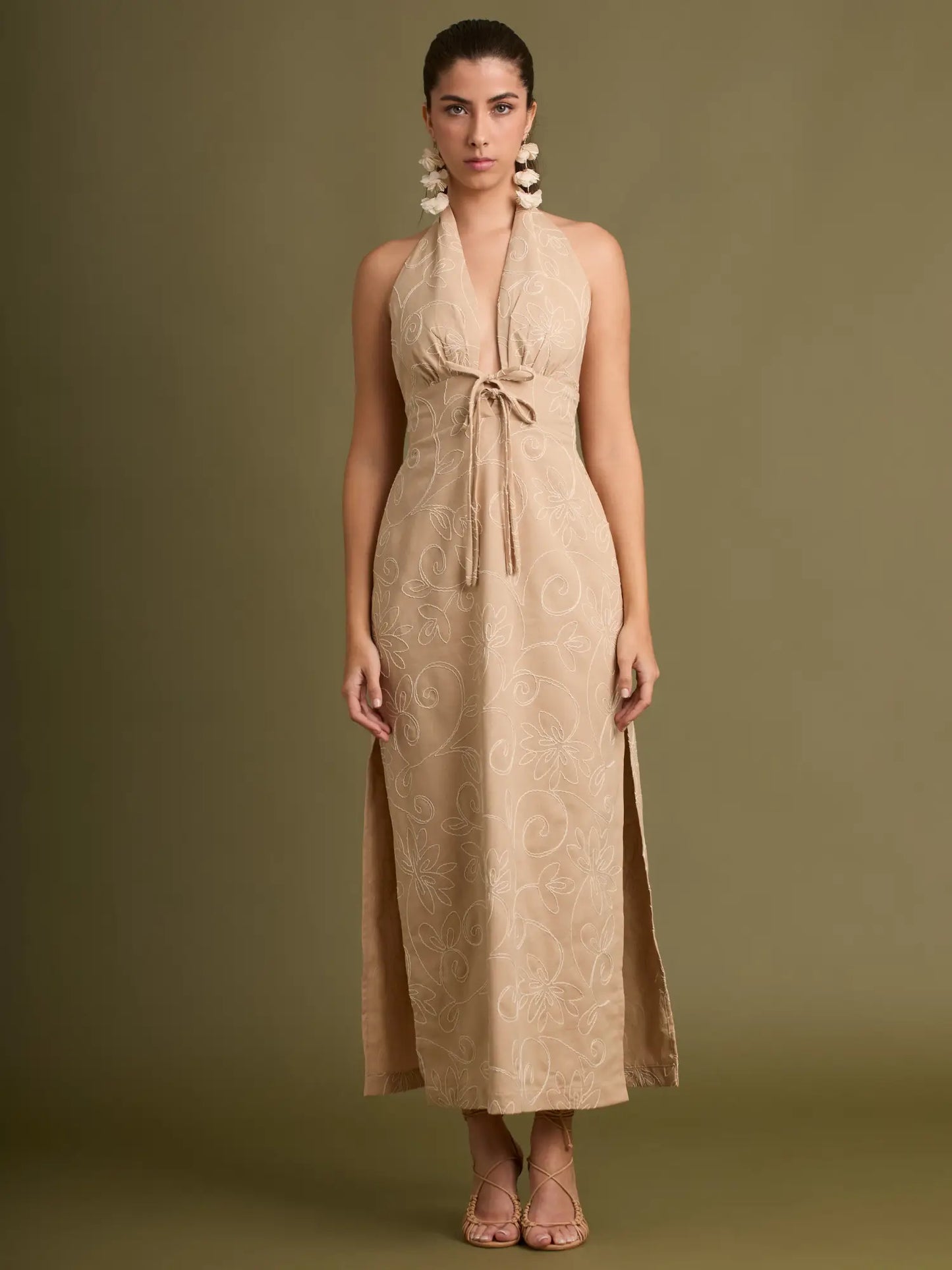 La combinación ideal de textura y estilo: bordado floral sobre base beige, silueta halter estilizada y abertura lateral que agrega dinamismo y sofisticación.