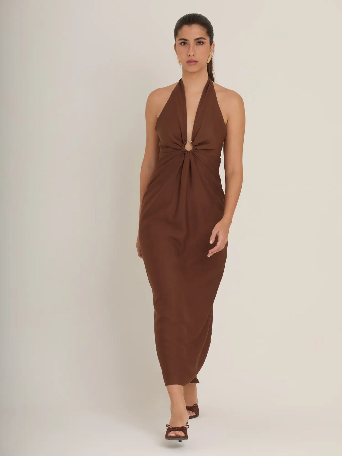 El vestido marrón minimalista ofrece líneas limpias, un escote halter estilizado y una falda midi elegante. Perfecto para quienes buscan un estilo sofisticado y depurado.