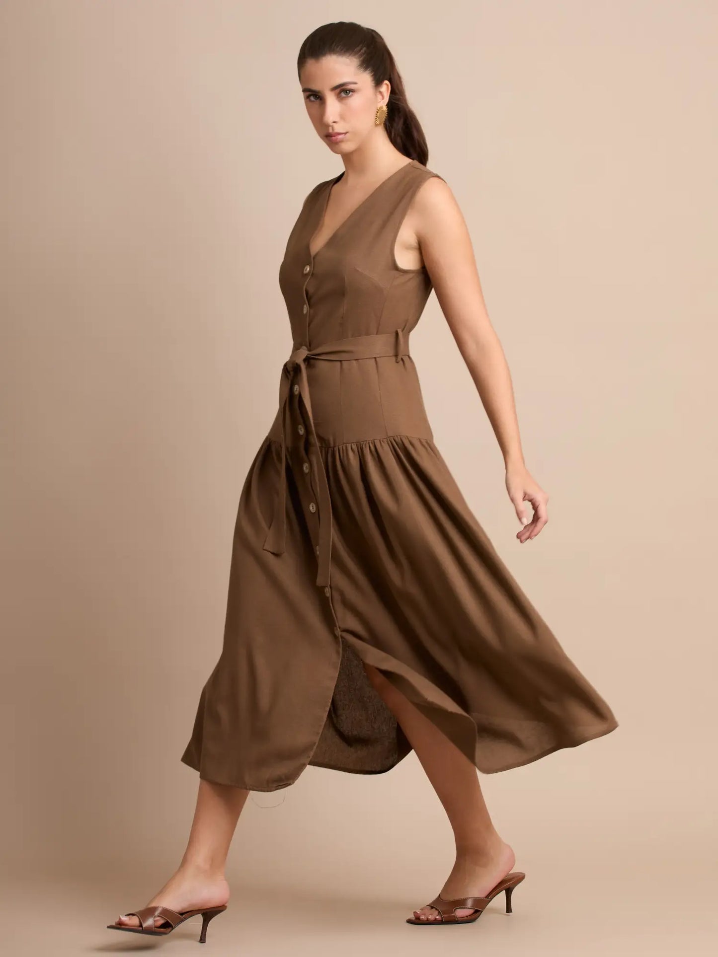 Su diseño presenta un cinturón anudado al frente que acentúa la cintura, complementado con una botonadura frontal que aporta un toque clásico y femenino.