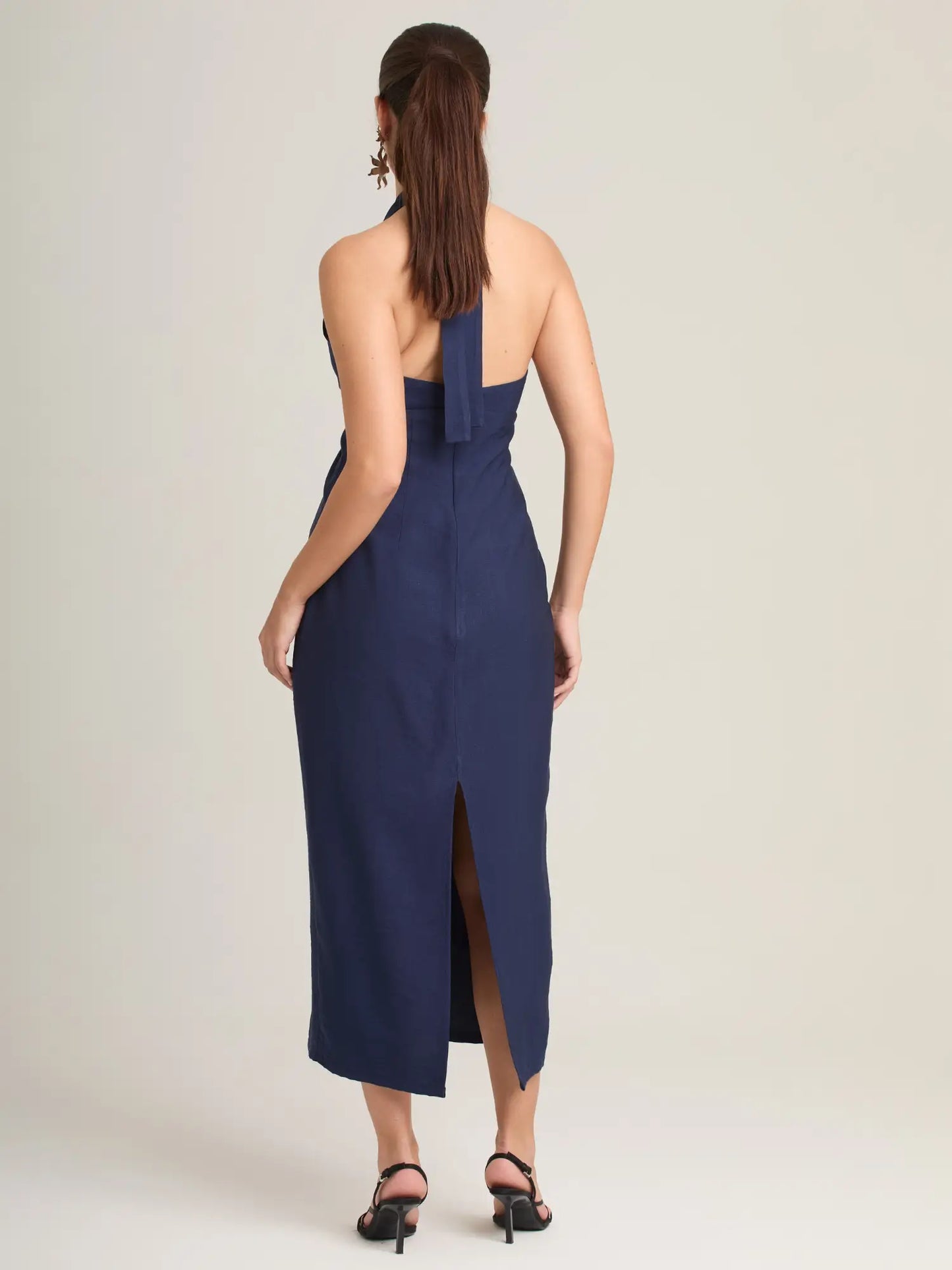 Este vestido midi azul marino combina un escote halter favorecedor con un detalle frontal que añade un toque moderno. Ideal para un look elegante y minimalista.
