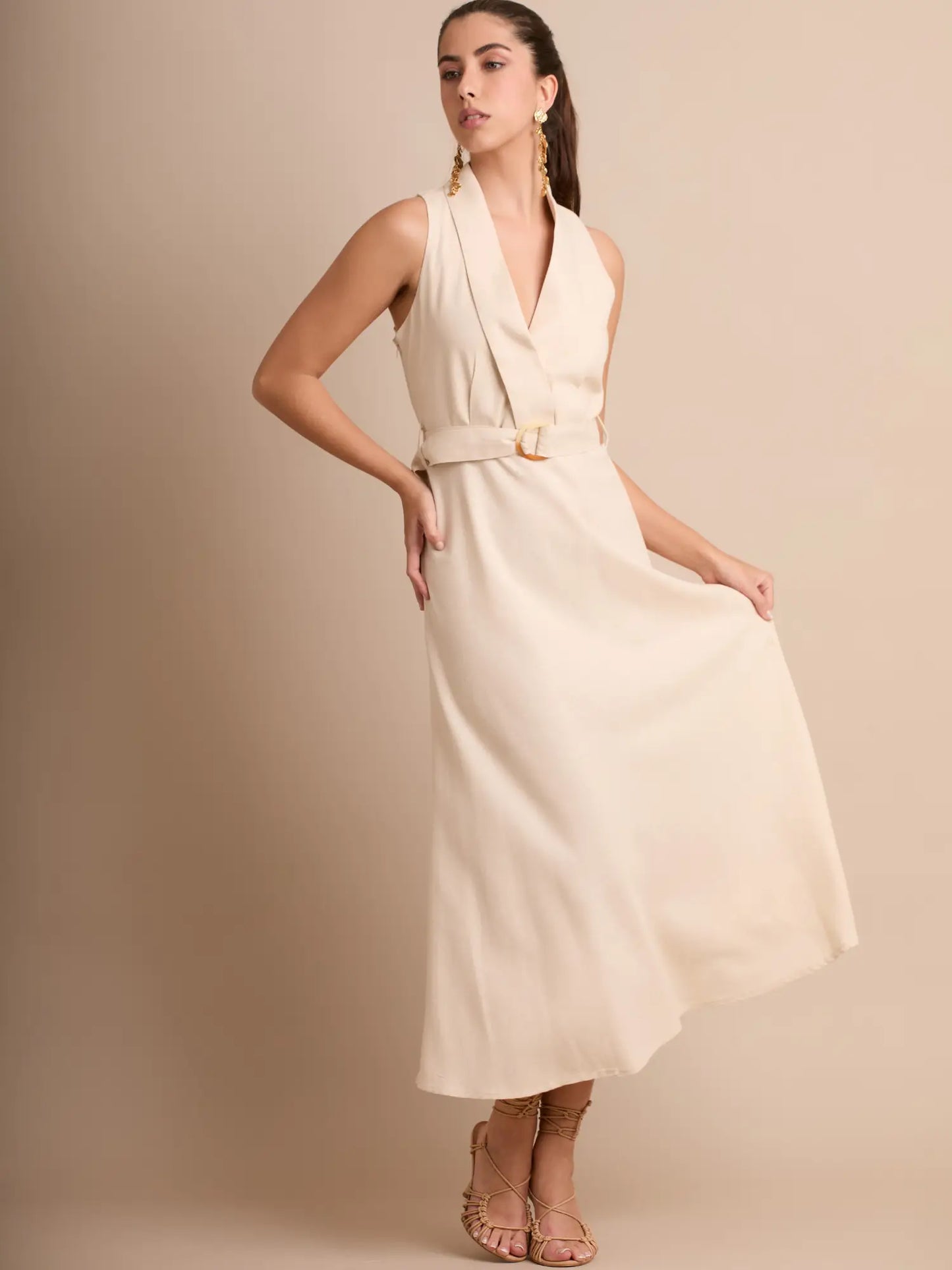Un vestido en tono neutro que resalta por su cuello solapa sofisticado y su cinturón integrado. Su caída fluida brinda un toque delicado y chic, perfecto para días cálidos o eventos semi-formales.