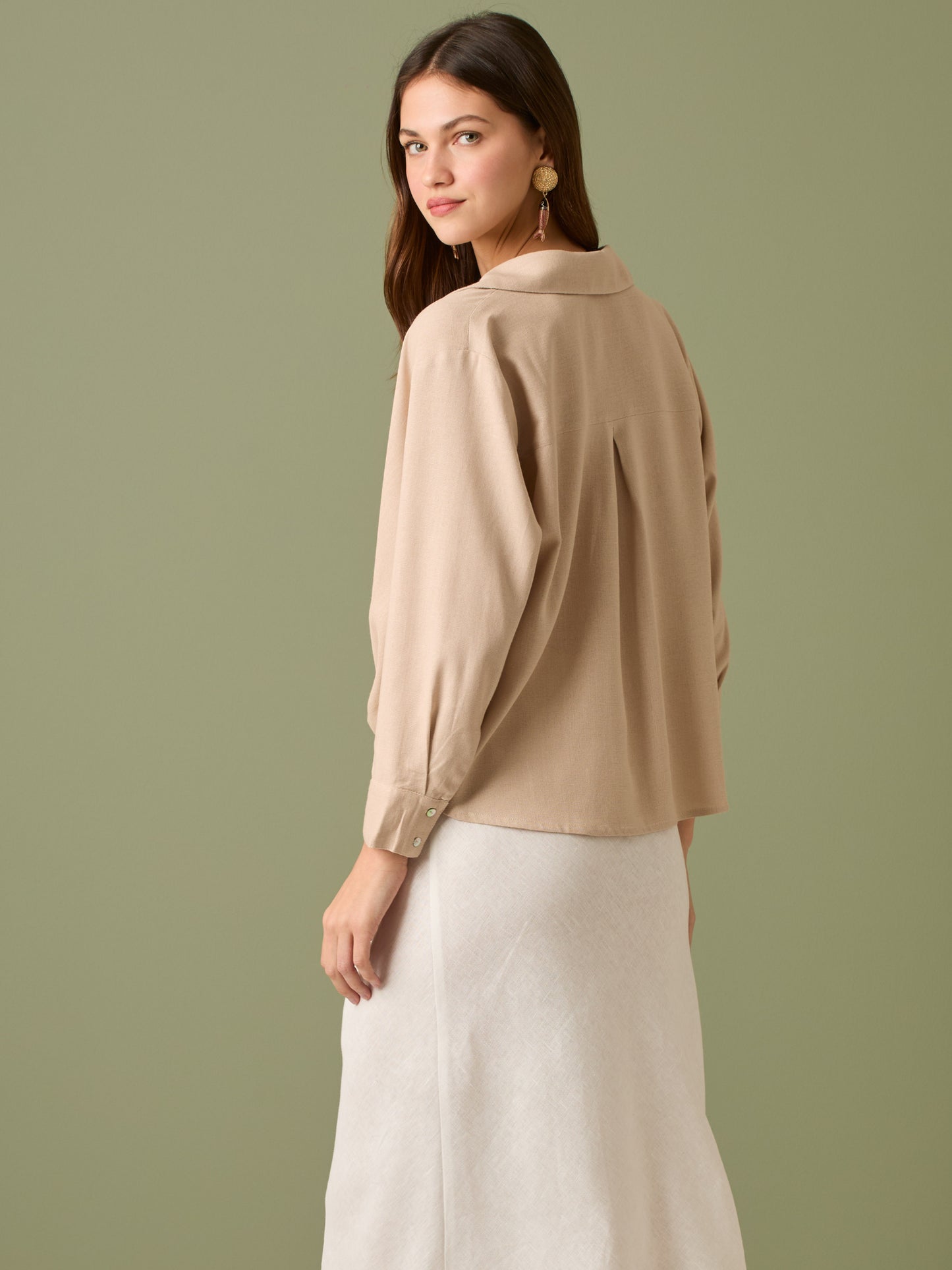 Esta blusa de manga larga tiene un estilo sofisticado y moderno. Presenta cuello clásico tipo camisero y un diseño de escote en "V" sutil que alarga visualmente el cuello. El detalle más destacado es el nudo frontal retorcido en la parte baja, que genera un efecto drapeado y asimétrico, aportando dinamismo y elegancia a la prenda. Los puños son anchos y estructurados, lo que refuerza el acabado pulido del diseño. Ideal para looks formales o smart-casual, combinada con pantalones de tiro alto o faldas.