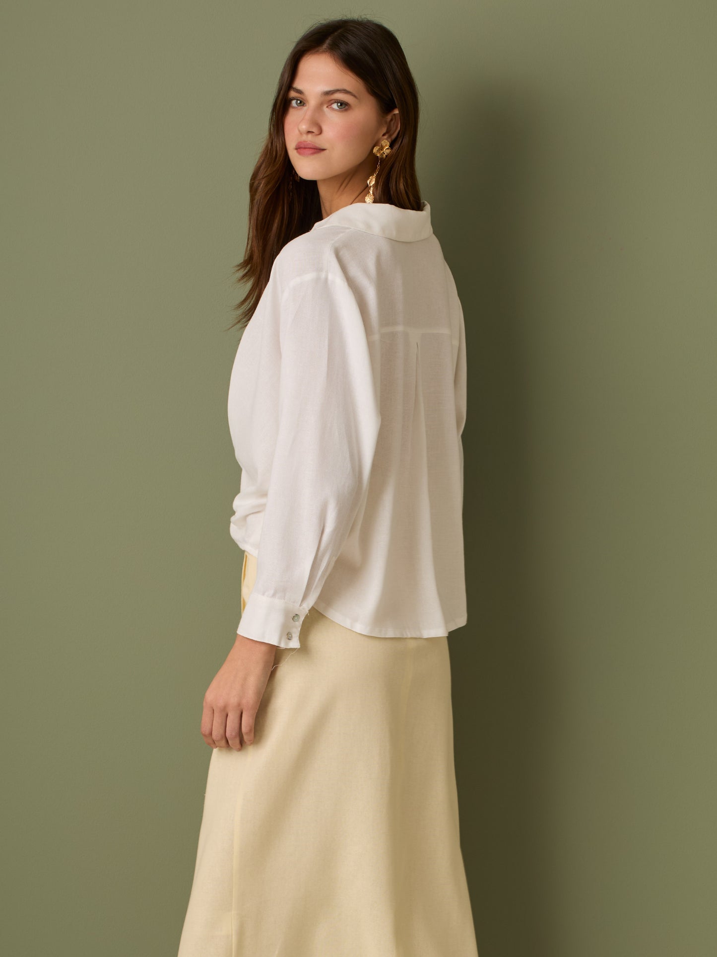 Esta blusa de manga larga tiene un estilo sofisticado y moderno. Presenta cuello clásico tipo camisero y un diseño de escote en "V" sutil que alarga visualmente el cuello. El detalle más destacado es el nudo frontal retorcido en la parte baja, que genera un efecto drapeado y asimétrico, aportando dinamismo y elegancia a la prenda. Los puños son anchos y estructurados, lo que refuerza el acabado pulido del diseño. Ideal para looks formales o smart-casual, combinada con pantalones de tiro alto o faldas.