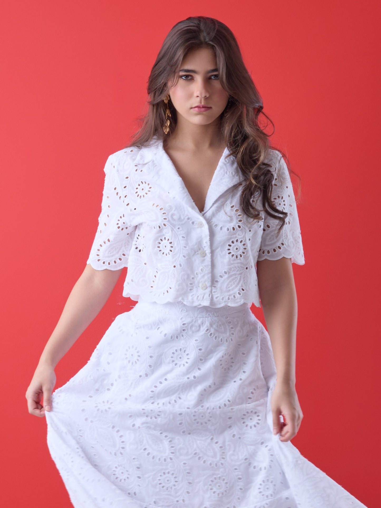 Con un diseño delicado y femenino, esta blusa corta presenta bordado calado en todo su contorno, aportando textura y un aire artesanal. El cuello camisero, la silueta relajada y las mangas cortas estructuradas la convierten en una prenda ideal para looks frescos y elegantes. Perfecta para combinar con faldas de talle alto o pantalones sutiles en ocasiones de día con un estilo impecable.