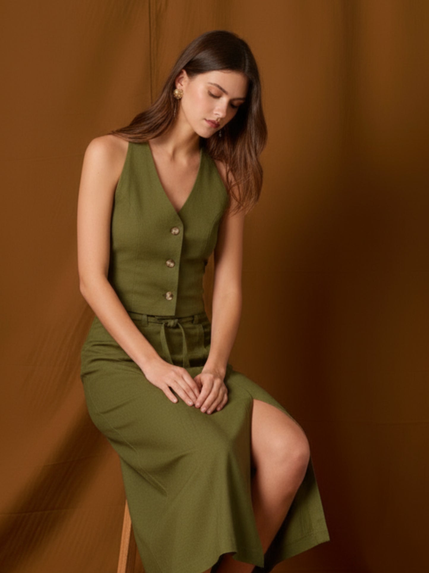 Chaleco-top sin mangas, de silueta entallada y escote en V que resalta el cuello. Lleva botones frontales visibles, pinzas que definen la figura y un pequeño bolsillo en el pecho. Largo a la cintura con bajo levemente curvo: ideal para llevar solo o en capas y completar conjuntos coordinados
Detalles:
Color: Olivo