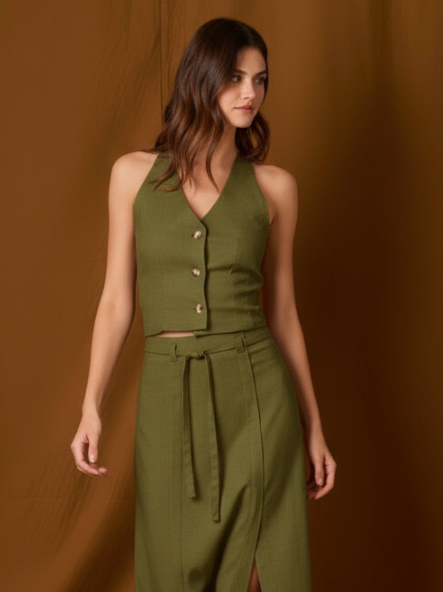 Chaleco-top sin mangas, de silueta entallada y escote en V que resalta el cuello. Lleva botones frontales visibles, pinzas que definen la figura y un pequeño bolsillo en el pecho. Largo a la cintura con bajo levemente curvo: ideal para llevar solo o en capas y completar conjuntos coordinados
Detalles:
Color: Olivo