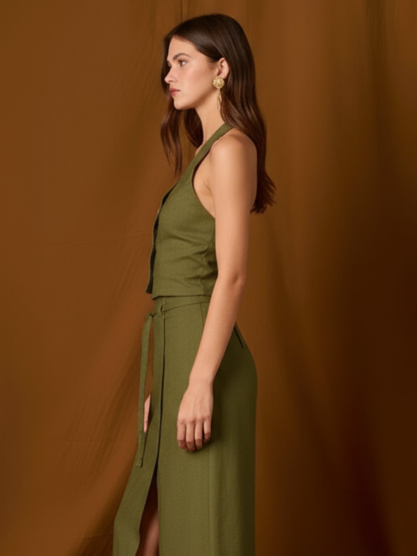 Chaleco-top sin mangas, de silueta entallada y escote en V que resalta el cuello. Lleva botones frontales visibles, pinzas que definen la figura y un pequeño bolsillo en el pecho. Largo a la cintura con bajo levemente curvo: ideal para llevar solo o en capas y completar conjuntos coordinados
Detalles:
Color: Olivo