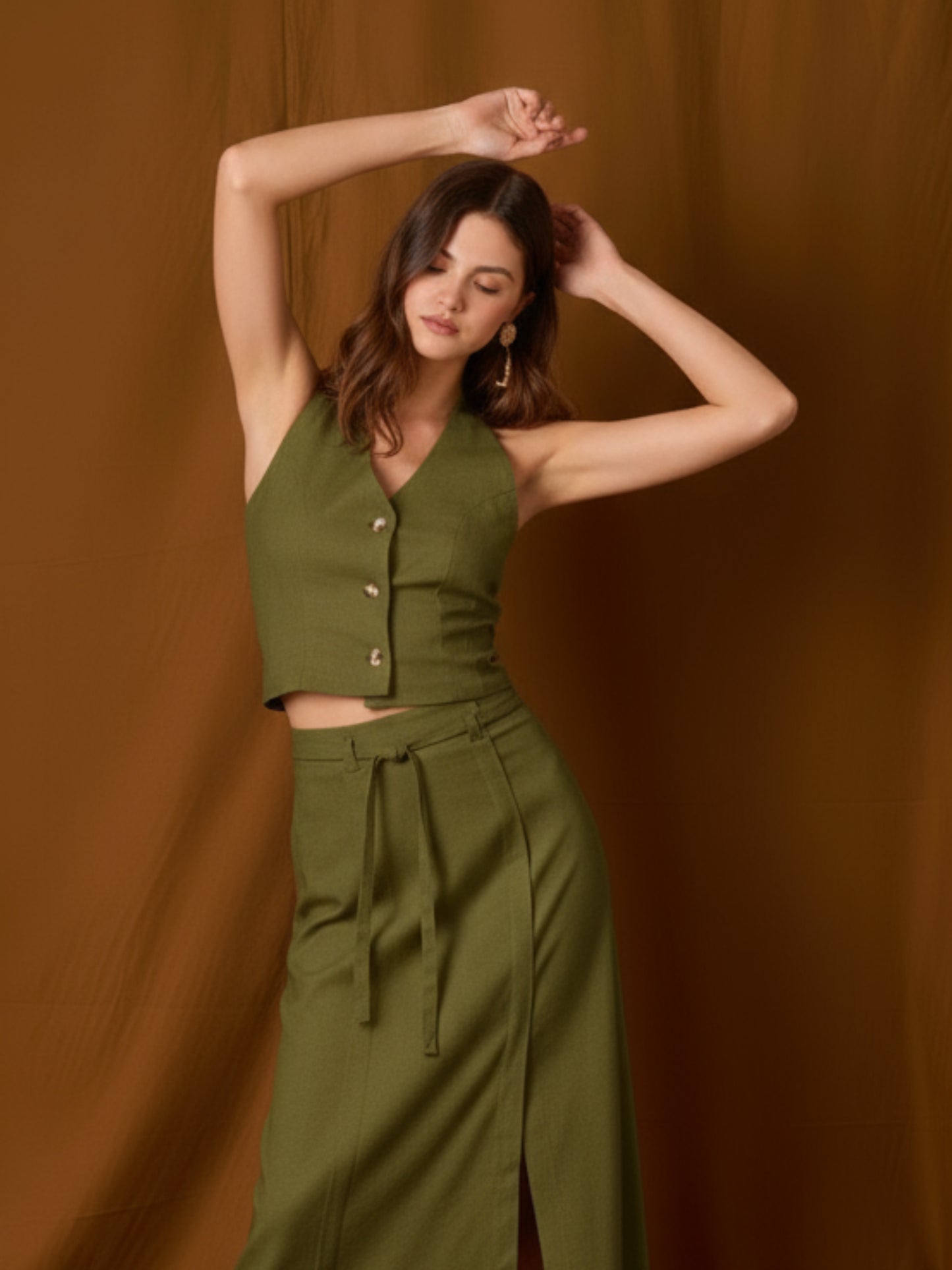 Chaleco-top sin mangas, de silueta entallada y escote en V que resalta el cuello. Lleva botones frontales visibles, pinzas que definen la figura y un pequeño bolsillo en el pecho. Largo a la cintura con bajo levemente curvo: ideal para llevar solo o en capas y completar conjuntos coordinados
Detalles:
Color: Olivo