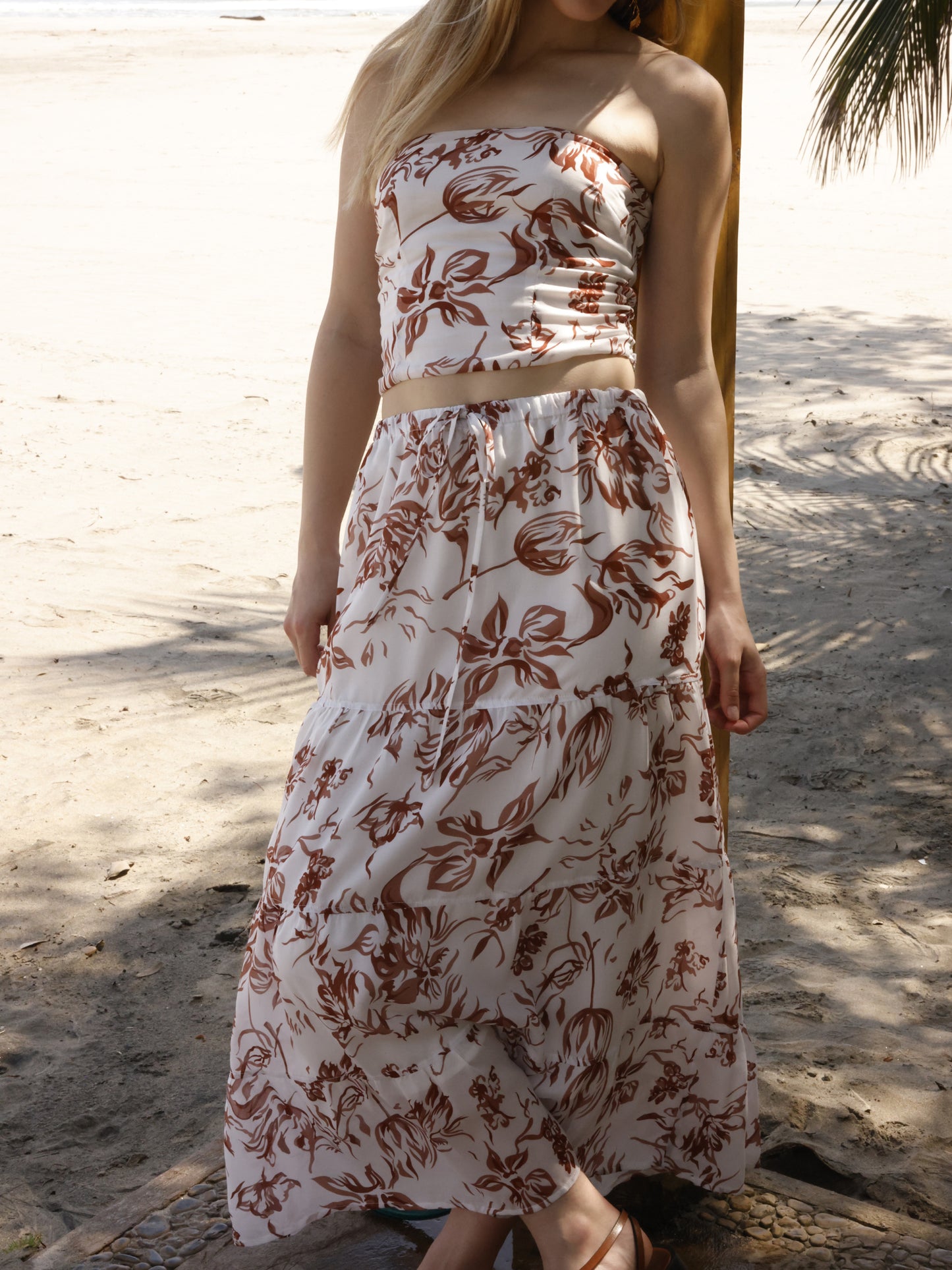 Esta falda es de corte largo, tipo maxi, confeccionada en una tela ligera ideal para climas cálidos. Presenta un estampado floral en tonos marrones sobre fondo blanco, lo que le da un estilo fresco y veraniego. Tiene un diseño de cintura alta con pretina plana que estiliza la figura y caída fluida con ligero vuelo, aportando movimiento al caminar. Es una prenda cómoda y elegante, perfecta para looks de playa o escapadas tropicales.
Detalles:
Color: Blanco
Material: 100% Lyocel