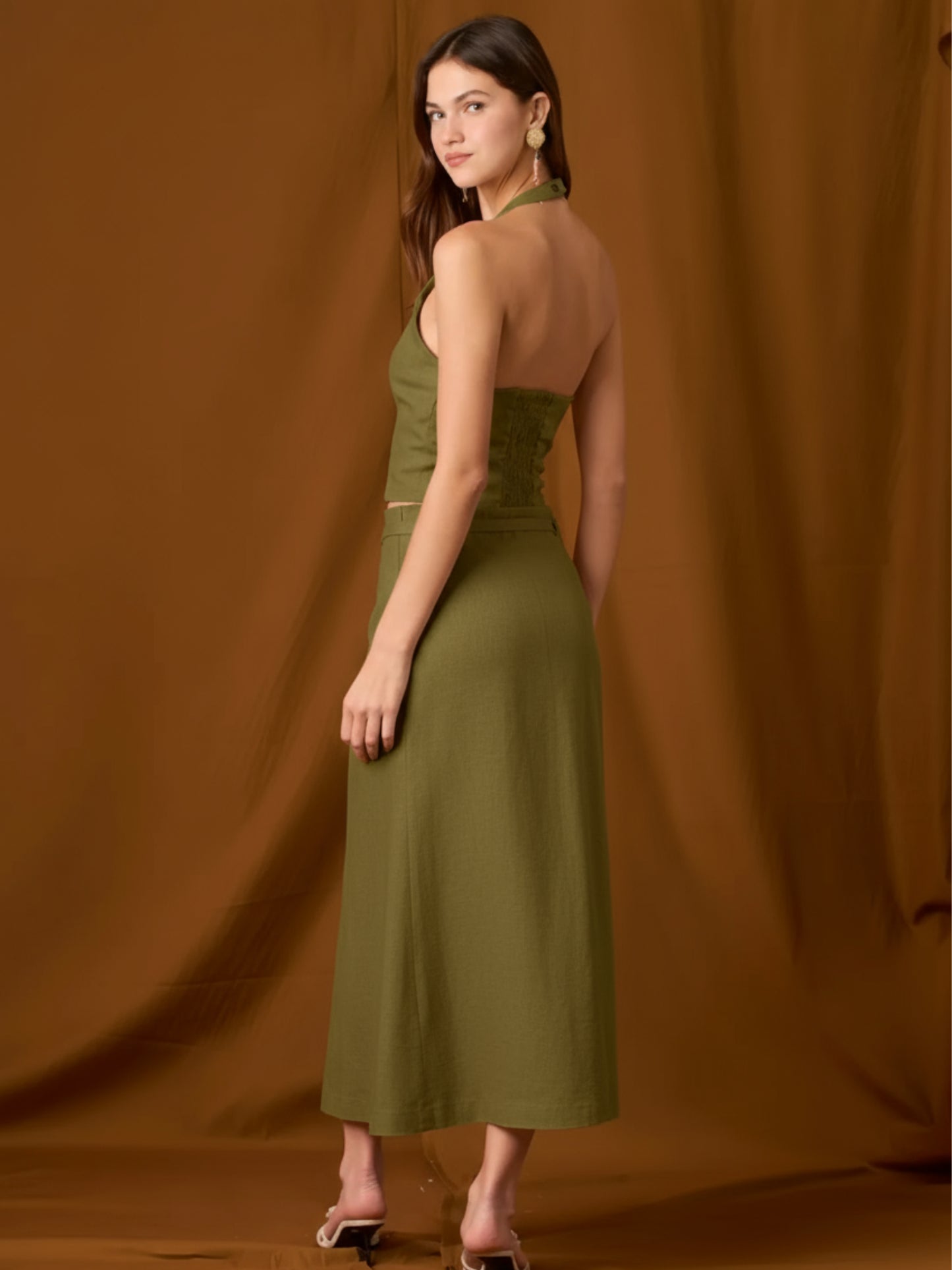 Falda midi de tiro alto con pretina y pasadores, cinturón delgado para ajustar y cruce tipo pareo al frente con abertura lateral que alarga la silueta. Caída recta con leve evasé y largo a media pierna para un movimiento fluido. Versátil y sofisticada para elevar tus looks de día o de noche.