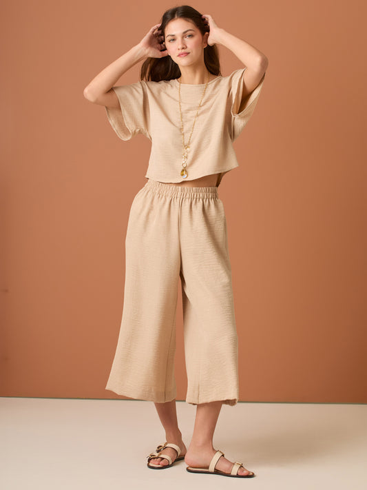 Con una silueta relajada y favorecedora, este pantalón amplio ofrece comodidad sin sacrificar estilo. Su pretina elástica asegura un ajuste cómodo y práctico, mientras que el largo al tobillo y la caída ligera lo convierten en una opción ideal para looks casuales sofisticados o días de movimiento con un aire minimalista y pulido.