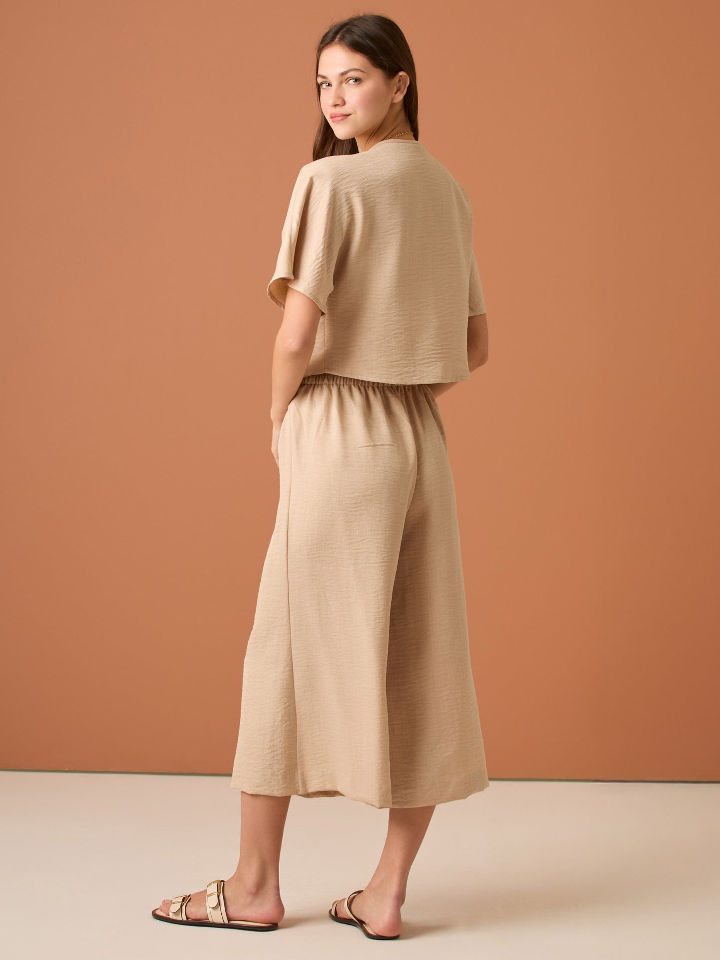 Con una silueta relajada y favorecedora, este pantalón amplio ofrece comodidad sin sacrificar estilo. Su pretina elástica asegura un ajuste cómodo y práctico, mientras que el largo al tobillo y la caída ligera lo convierten en una opción ideal para looks casuales sofisticados o días de movimiento con un aire minimalista y pulido.