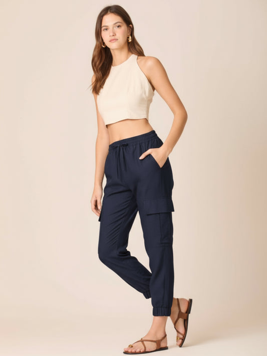 Este pantalón combina comodidad y estilo en un diseño moderno. Presenta pretina elástica con cordón ajustable que se adapta perfectamente a la cintura, bolsillos laterales tipo cargo que aportan un aire práctico y urbano, y terminaciones con elástico en los tobillos que estilizan la silueta. Su corte relajado lo convierte en una prenda versátil y actual, ideal para un look casual y sofisticado al mismo tiempo. Perfecto para quienes buscan frescura y dinamismo sin perder elegancia.