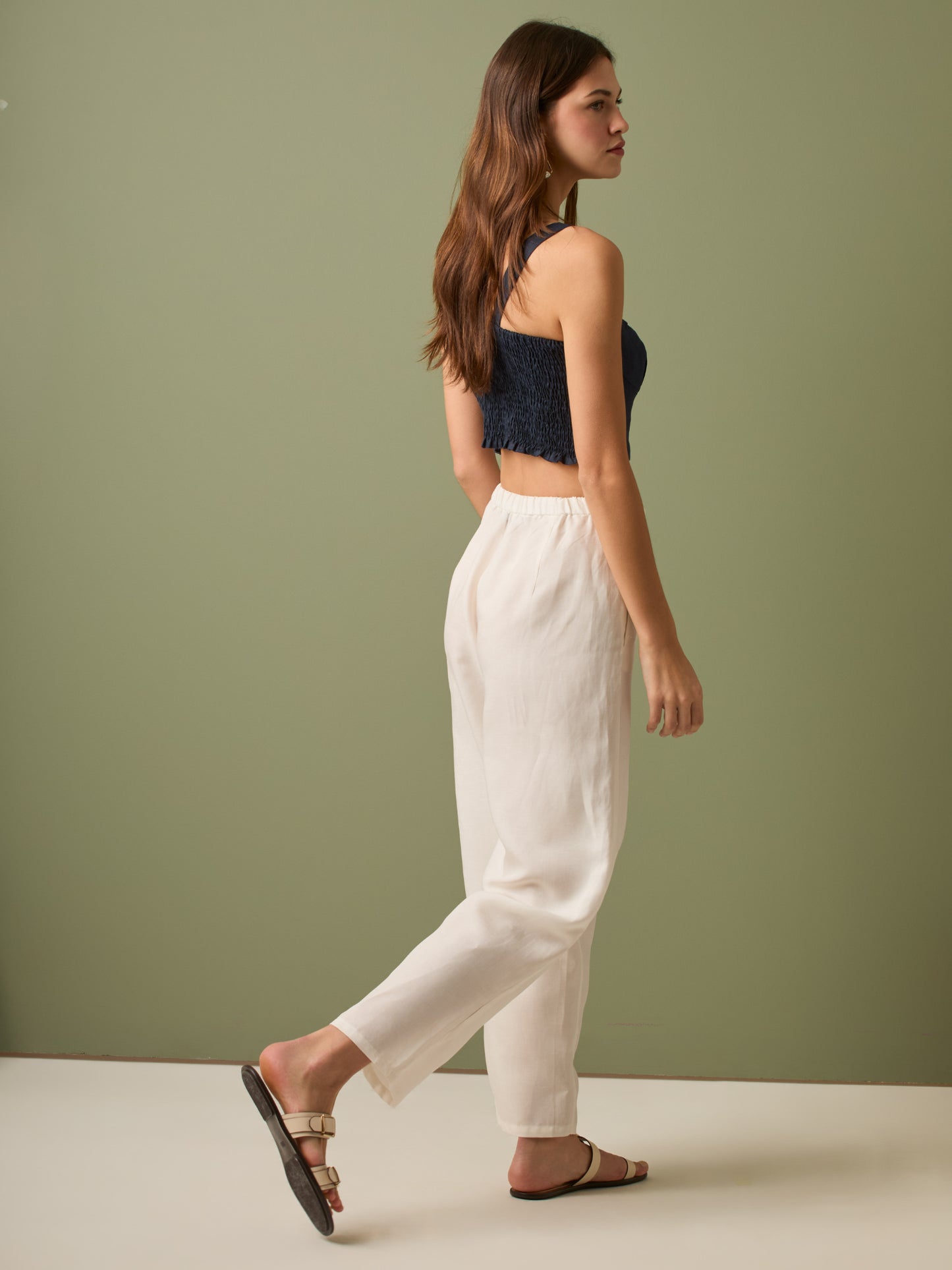 Pantalón de tiro medio con cintura elástica y cordón ajustable. Silueta relajada que cae con volumen en la cadera y se afina al tobillo, con bolsillos laterales y cortes decorativos en la pierna. Largo al tobillo con pequeña abertura en el bajo: la base moderna y versátil para elevar looks de día o de noche.