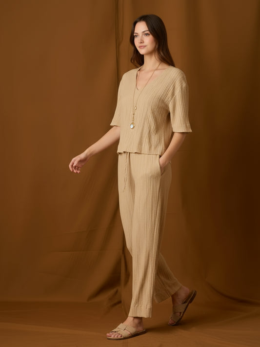 Pantalón fluido de silueta relajada y tiro medio, con pretina elástica y jareta ajustable. Pernera recta-amplia hasta el tobillo, bolsillos laterales y textura arrugada que aporta movimiento. Cómodo y versátil para el día a día o viajes; combínalo con tops mínima o la blusa a juego.