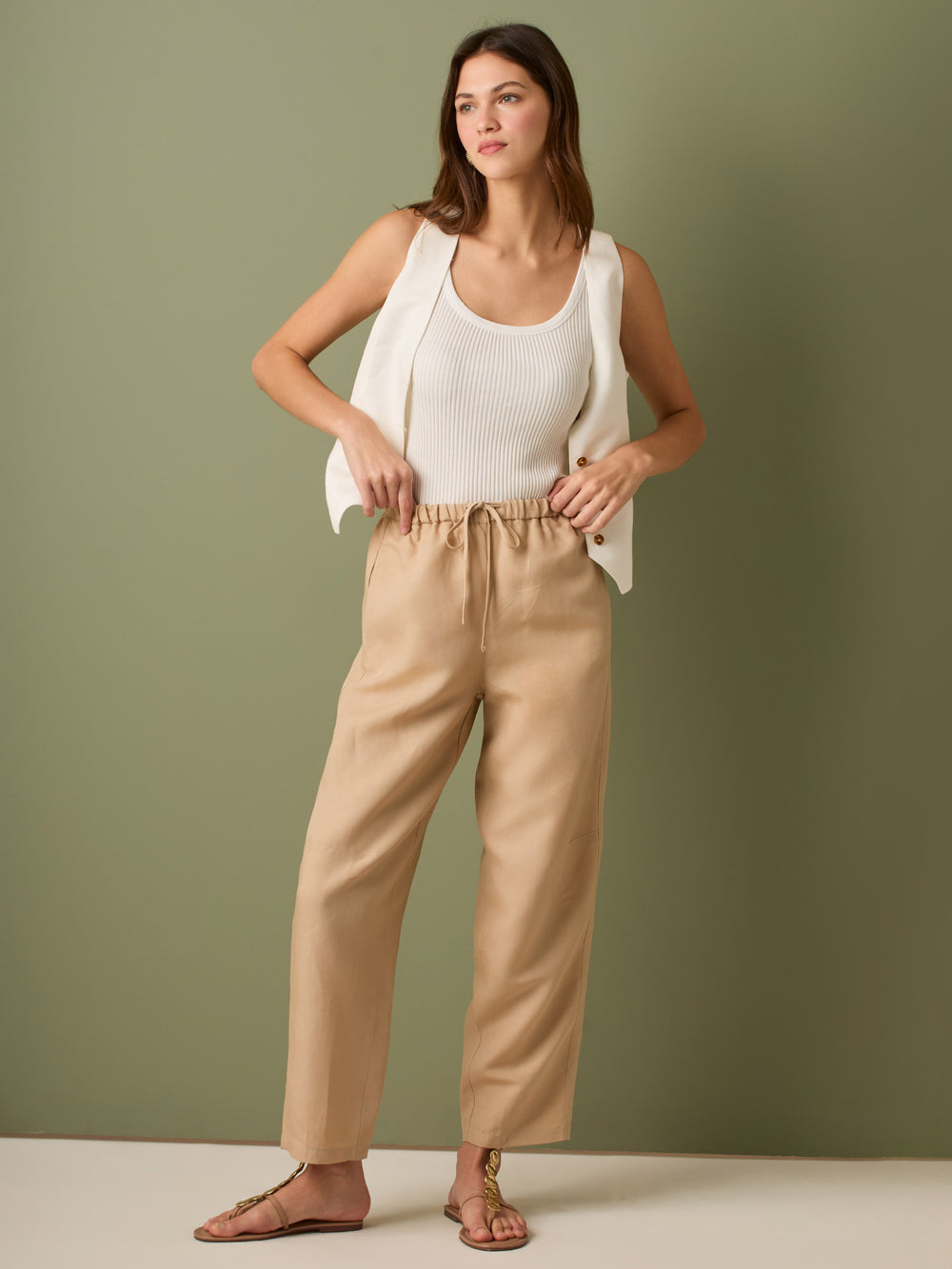 Pantalón de tiro medio con cintura elástica y cordón ajustable. Silueta relajada que cae con volumen en la cadera y se afina al tobillo, con bolsillos laterales y cortes decorativos en la pierna. Largo al tobillo con pequeña abertura en el bajo: la base moderna y versátil para elevar looks de día o de noche.
Detalles:
Color: Sand
Material: 77% Tencel 23% Lino 100% Rayón