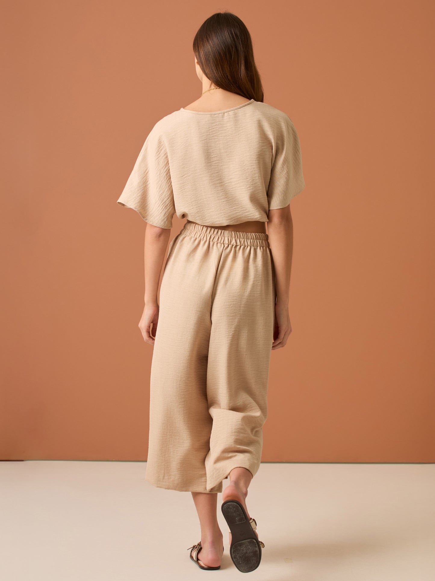 Con una silueta relajada y favorecedora, este pantalón amplio ofrece comodidad sin sacrificar estilo. Su pretina elástica asegura un ajuste cómodo y práctico, mientras que el largo al tobillo y la caída ligera lo convierten en una opción ideal para looks casuales sofisticados o días de movimiento con un aire minimalista y pulido.