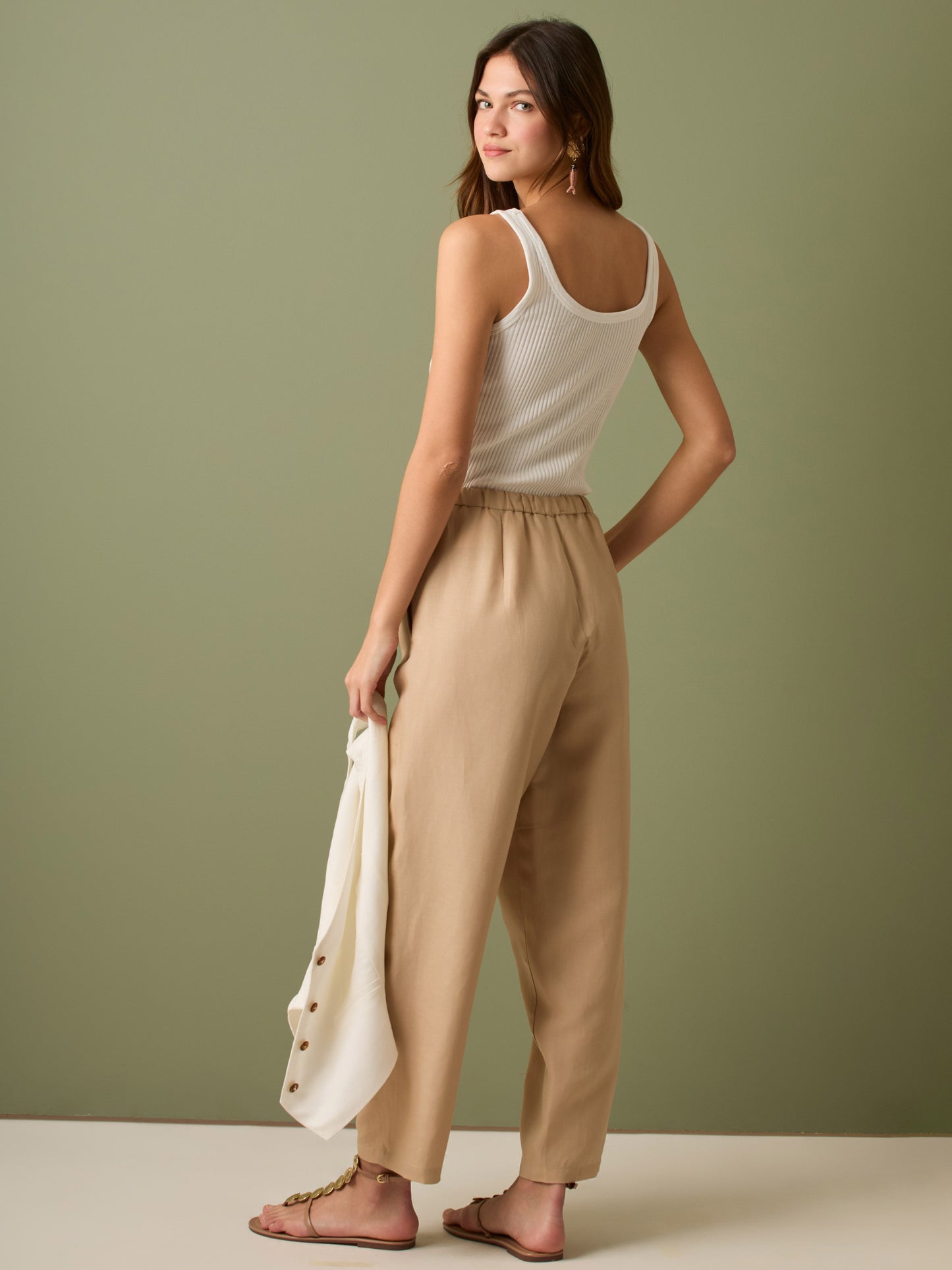 Pantalón de tiro medio con cintura elástica y cordón ajustable. Silueta relajada que cae con volumen en la cadera y se afina al tobillo, con bolsillos laterales y cortes decorativos en la pierna. Largo al tobillo con pequeña abertura en el bajo: la base moderna y versátil para elevar looks de día o de noche.
Detalles:
Color: Sand
Material: 77% Tencel 23% Lino 100% Rayón