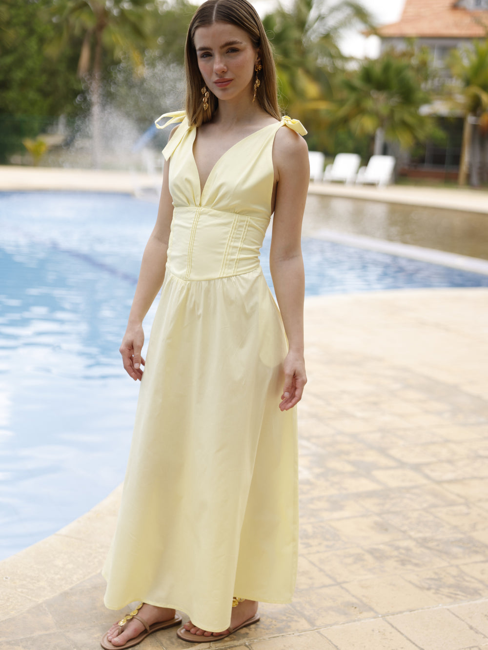 Este vestido presenta un diseño elegante y femenino. Tiene un escote en "V" cruzado que estiliza el busto y una cintura ancha tipo fajón que define la silueta. Los tirantes se anudan sobre los hombros, agregando un toque delicado y ajustable al diseño. La falda cae en corte evasé hasta los tobillos, con una caída fluida que favorece el movimiento. Su estilo atemporal lo hace ideal tanto para eventos de día como para cenas o celebraciones formales. Puede combinarse con tacones o sandalias.