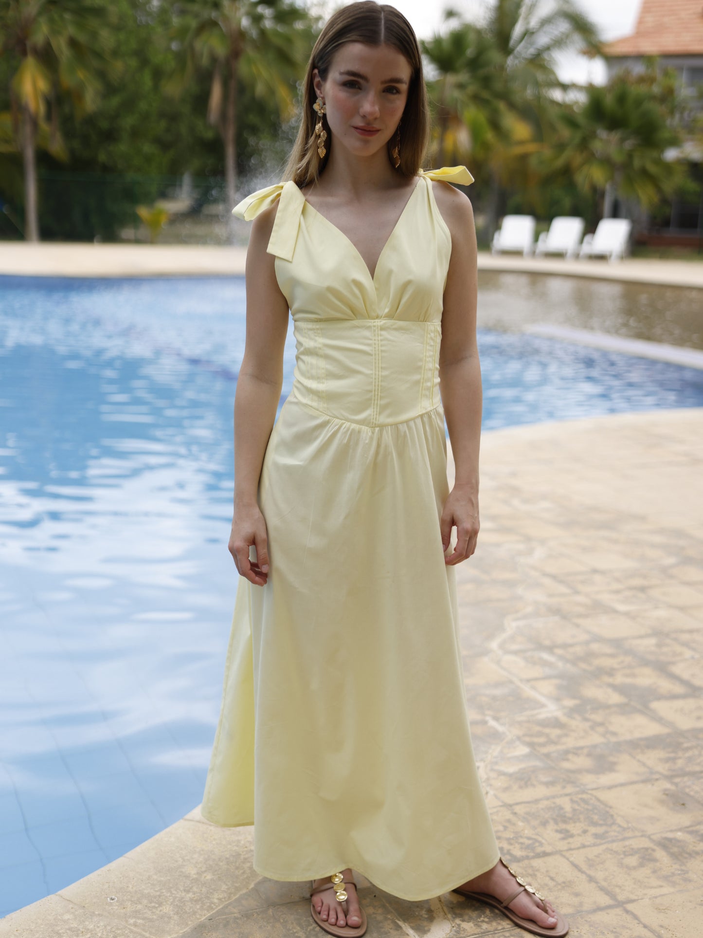 Este vestido presenta un diseño elegante y femenino. Tiene un escote en "V" cruzado que estiliza el busto y una cintura ancha tipo fajón que define la silueta. Los tirantes se anudan sobre los hombros, agregando un toque delicado y ajustable al diseño. La falda cae en corte evasé hasta los tobillos, con una caída fluida que favorece el movimiento. Su estilo atemporal lo hace ideal tanto para eventos de día como para cenas o celebraciones formales. Puede combinarse con tacones o sandalias.