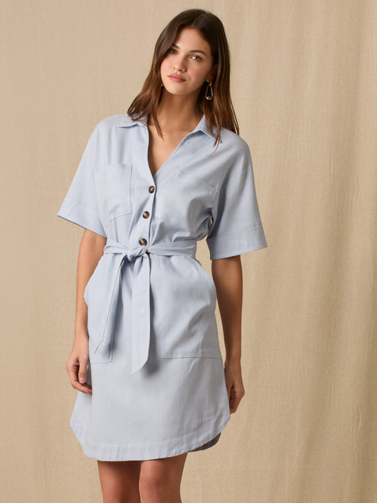Este vestido camisero de silueta recta combina la estructura de una prenda utilitaria con la frescura de un look contemporáneo. Con cuello tipo solapa, botones frontales contrastantes y bolsillos superiores de parche, incorpora un cinturón del mismo tejido que define la cintura y aporta feminidad. El largo sobre la rodilla lo convierte en una opción versátil para días cálidos, perfecta para el trabajo, una salida casual o un look urbano pulido.