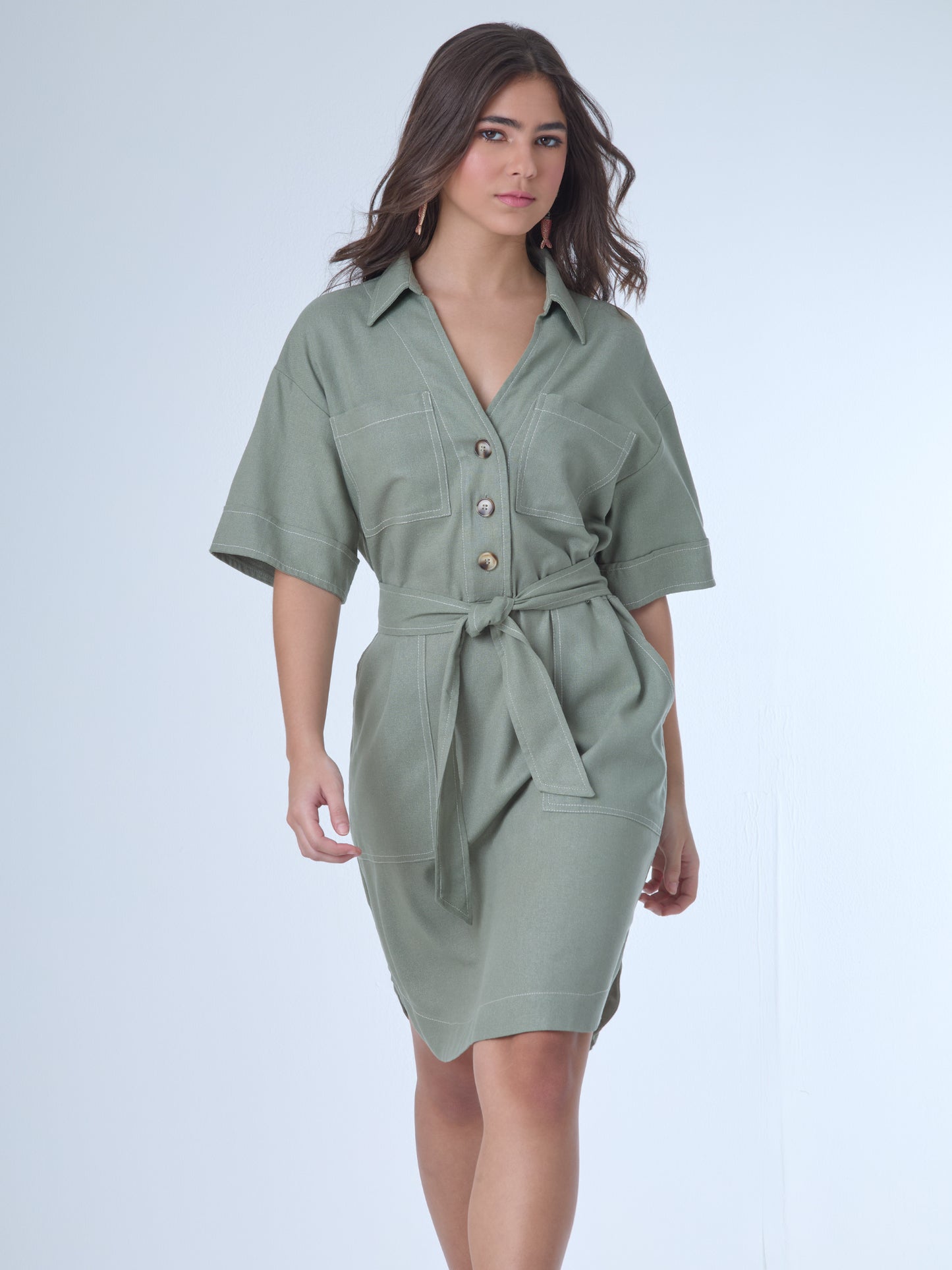 Este vestido camisero de silueta recta combina la estructura de una prenda utilitaria con la frescura de un look contemporáneo. Con cuello tipo solapa, botones frontales contrastantes y bolsillos superiores de parche, incorpora un cinturón del mismo tejido que define la cintura y aporta feminidad. El largo sobre la rodilla lo convierte en una opción versátil para días cálidos, perfecta para el trabajo, una salida casual o un look urbano pulido.