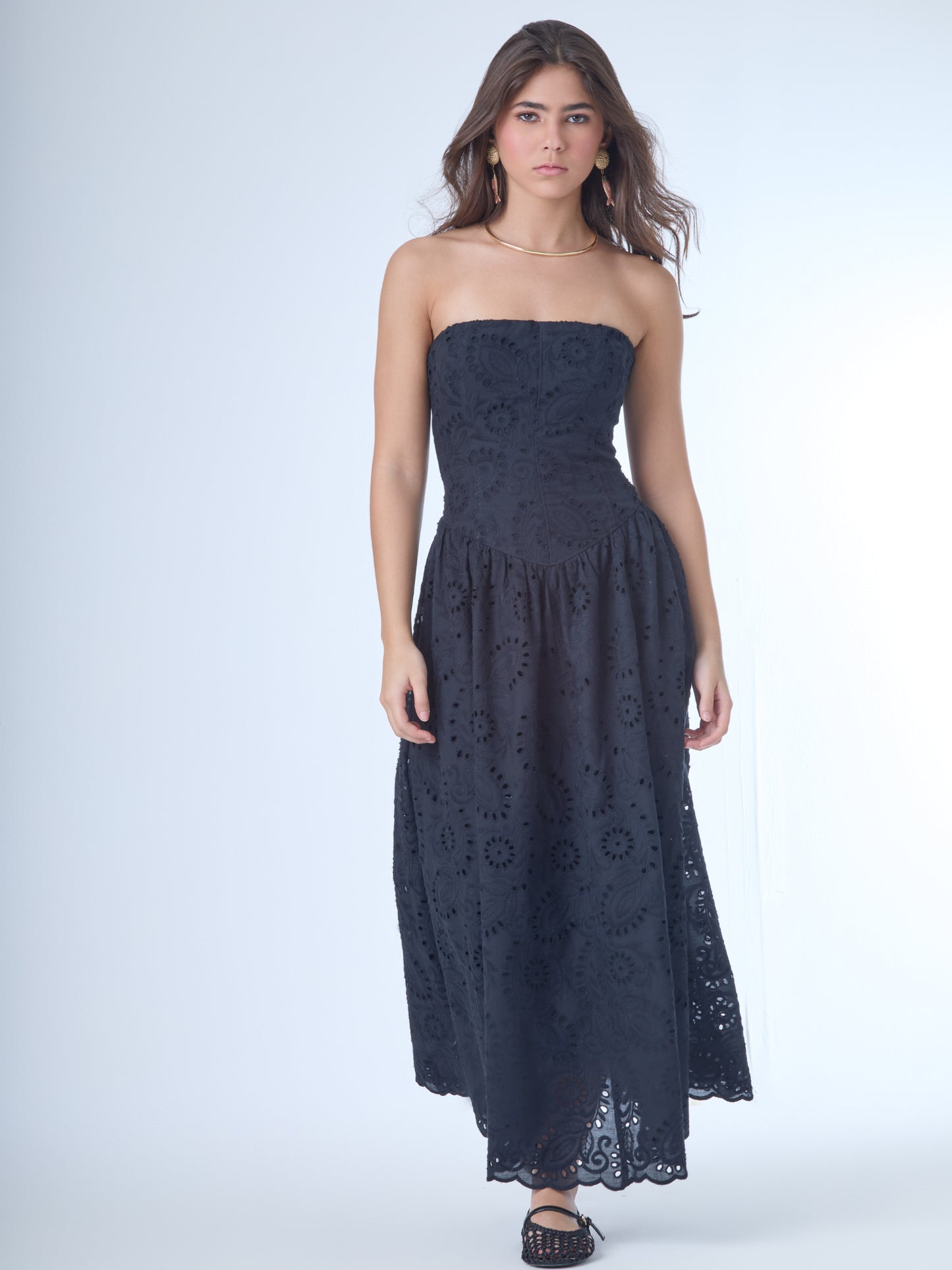 Este elegante vestido strapless, ideal para resaltar los hombros y el cuello con un estilo sofisticado y femenino. Está confeccionado en una telacon bordado inglés, que combina patrones florales y geométricos calados, aportando textura y un aire romántico.