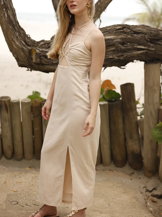 Vestido largo de tirantes delgados con escote halter. Tiene un detalle fruncido en el busto con abertura frontal y un pequeño corte debajo del pecho. La falda incluye una abertura frontal que aporta movimiento y frescura al diseño. Silueta ajustada al cuerpo con caída fluida. Ideal para un look de playa o verano.