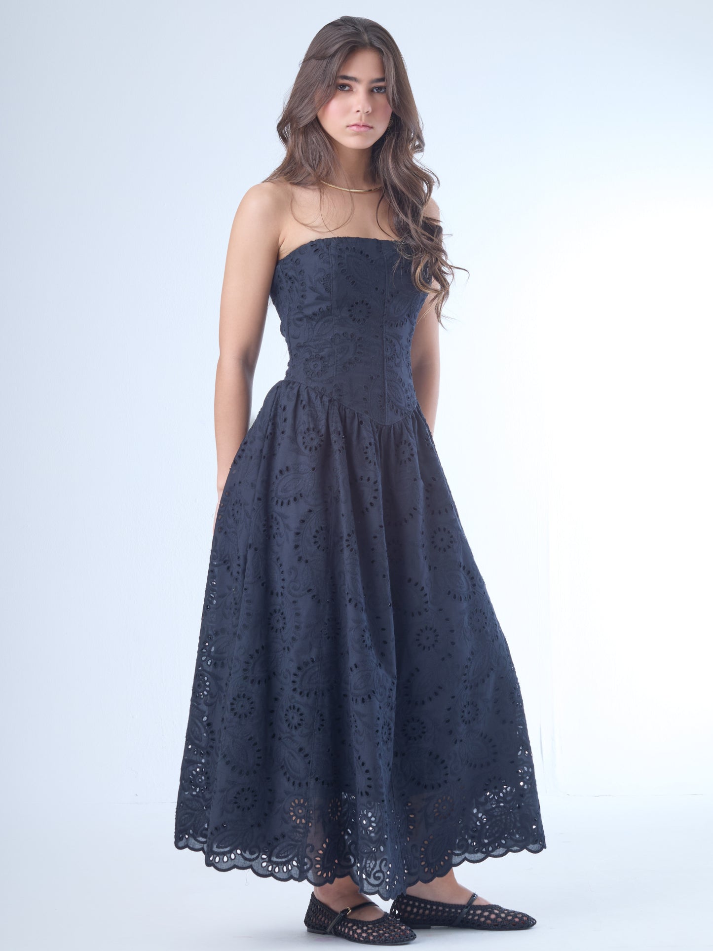 Este elegante vestido strapless, ideal para resaltar los hombros y el cuello con un estilo sofisticado y femenino. Está confeccionado en una telacon bordado inglés, que combina patrones florales y geométricos calados, aportando textura y un aire romántico.