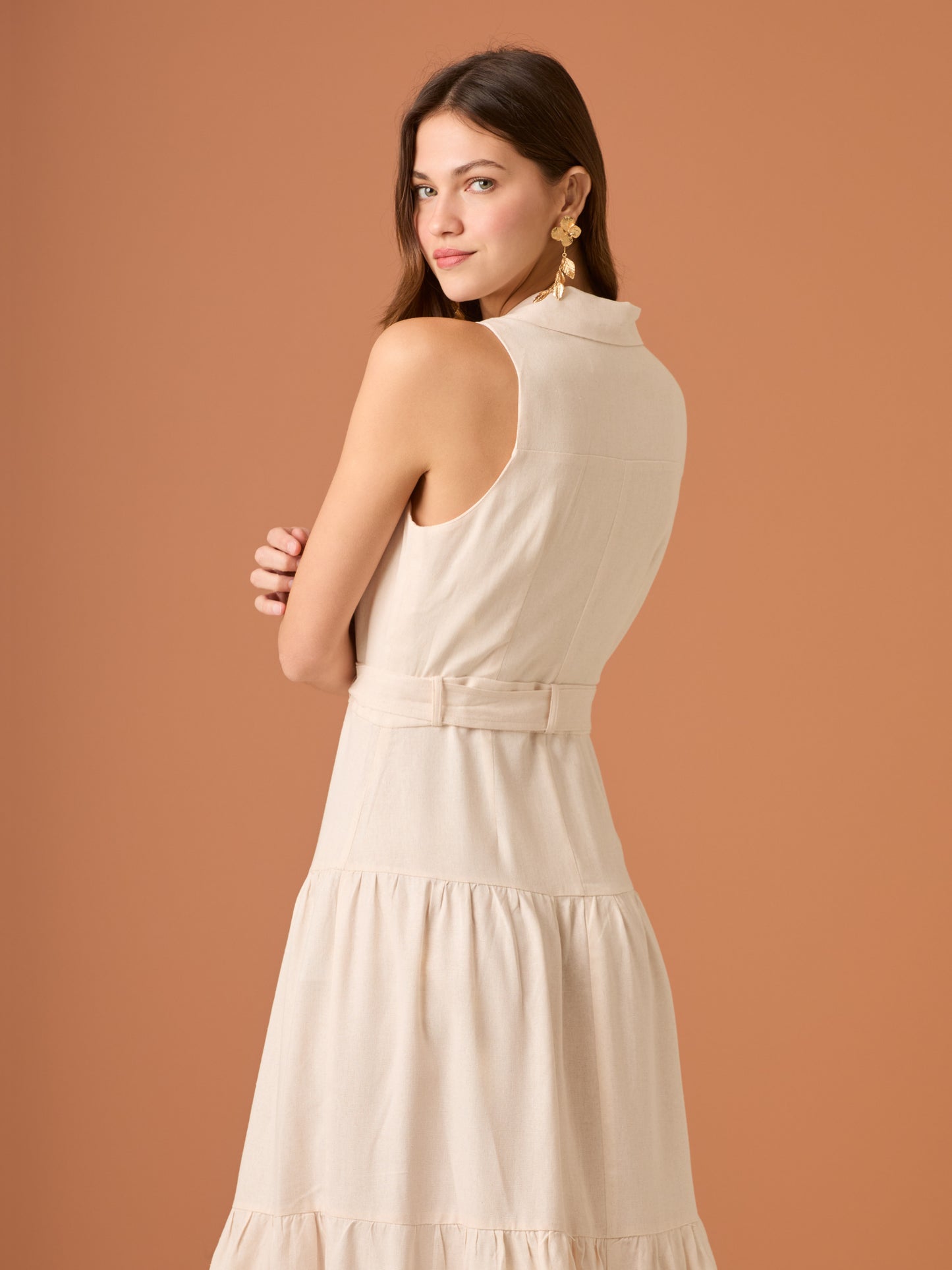 Vestido midi sin mangas con solapa tipo sastre, botonadura frontal y corte en la cintura que se ajusta con lazo, terminado en falda con volantes amplios