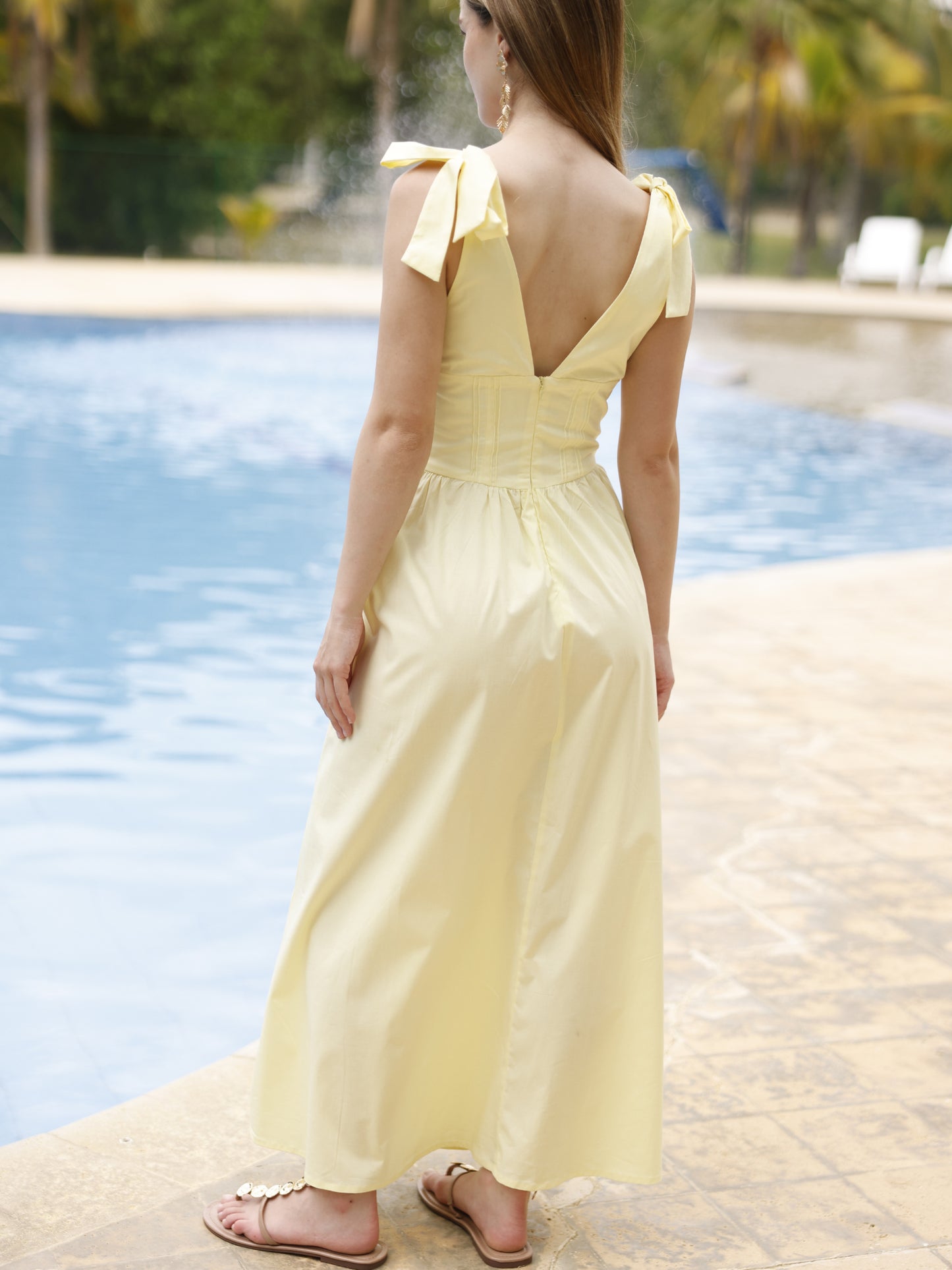 Este vestido presenta un diseño elegante y femenino. Tiene un escote en "V" cruzado que estiliza el busto y una cintura ancha tipo fajón que define la silueta. Los tirantes se anudan sobre los hombros, agregando un toque delicado y ajustable al diseño. La falda cae en corte evasé hasta los tobillos, con una caída fluida que favorece el movimiento. Su estilo atemporal lo hace ideal tanto para eventos de día como para cenas o celebraciones formales. Puede combinarse con tacones o sandalias.