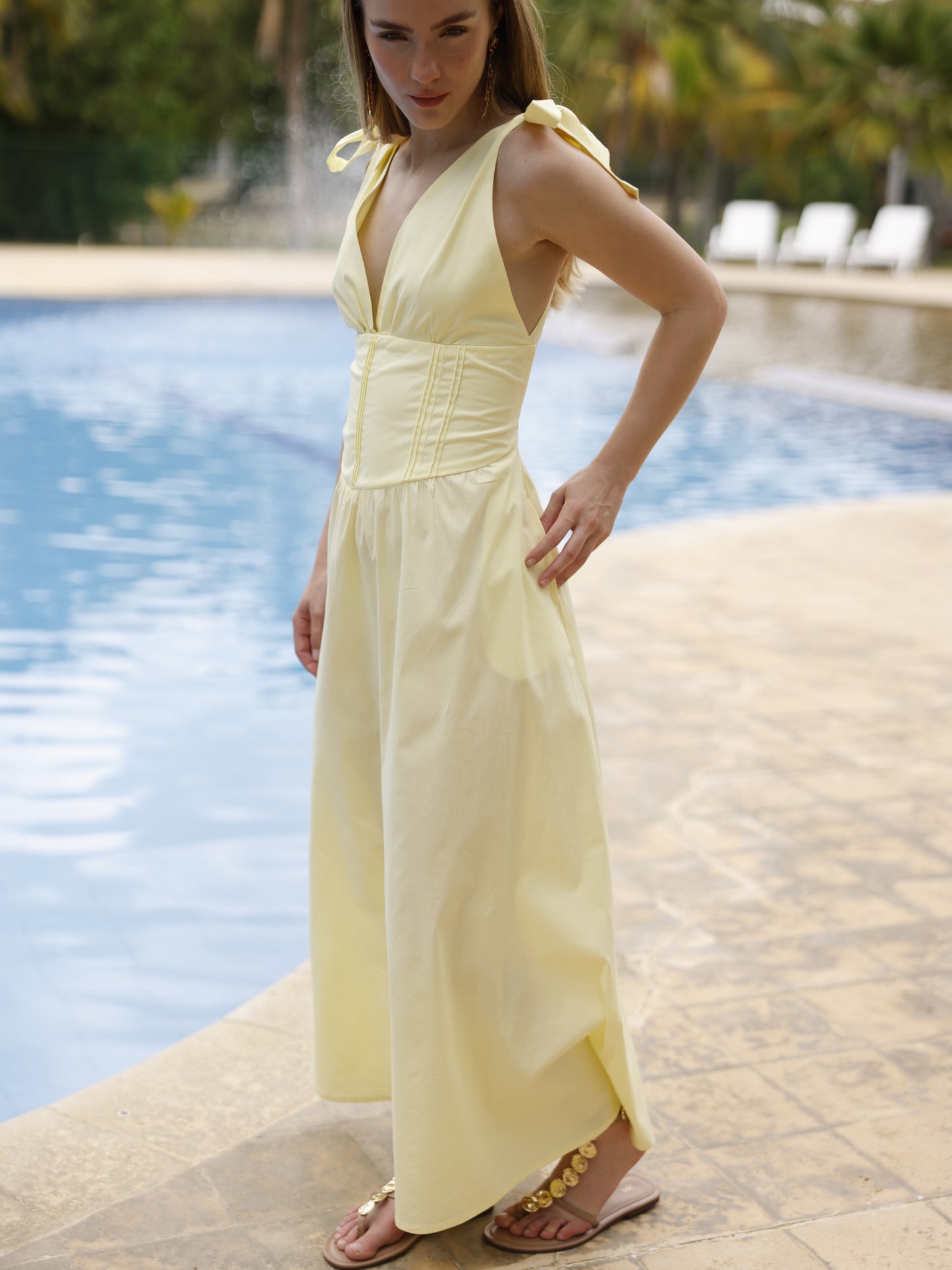 Este vestido presenta un diseño elegante y femenino. Tiene un escote en "V" cruzado que estiliza el busto y una cintura ancha tipo fajón que define la silueta. Los tirantes se anudan sobre los hombros, agregando un toque delicado y ajustable al diseño. La falda cae en corte evasé hasta los tobillos, con una caída fluida que favorece el movimiento. Su estilo atemporal lo hace ideal tanto para eventos de día como para cenas o celebraciones formales. Puede combinarse con tacones o sandalias.