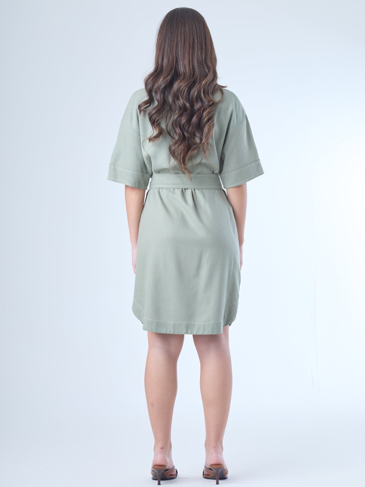 Este vestido camisero de silueta recta combina la estructura de una prenda utilitaria con la frescura de un look contemporáneo. Con cuello tipo solapa, botones frontales contrastantes y bolsillos superiores de parche, incorpora un cinturón del mismo tejido que define la cintura y aporta feminidad. El largo sobre la rodilla lo convierte en una opción versátil para días cálidos, perfecta para el trabajo, una salida casual o un look urbano pulido.