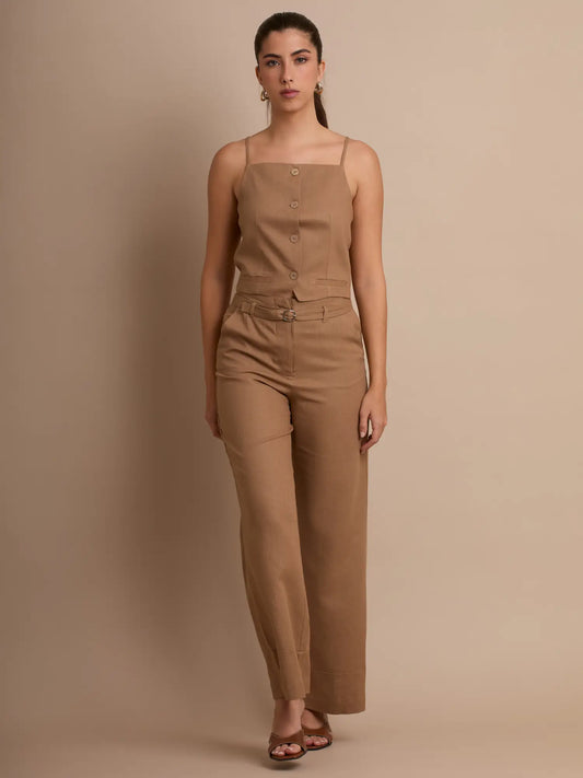 Una blusa ligera y elegante en tono beige, diseñada con botones frontales, tirantes delgados y un corte limpio que realza la figura. Ideal para looks minimalistas y combinaciones versátiles.