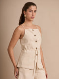 Esta blusa de tirantes beige destaca por sus botones tipo carey y sus bolsillos frontales tipo parche. El cinturón integrado permite ajustar la prenda al cuerpo, creando un look fresco y estructurado.
