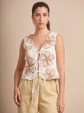 El chaleco Corfú destaca por su bordado floral artesanal en tonos tierra y sus lazos frontales, que añaden un toque femenino y bohemio. Ideal para looks frescos y veraniegos.