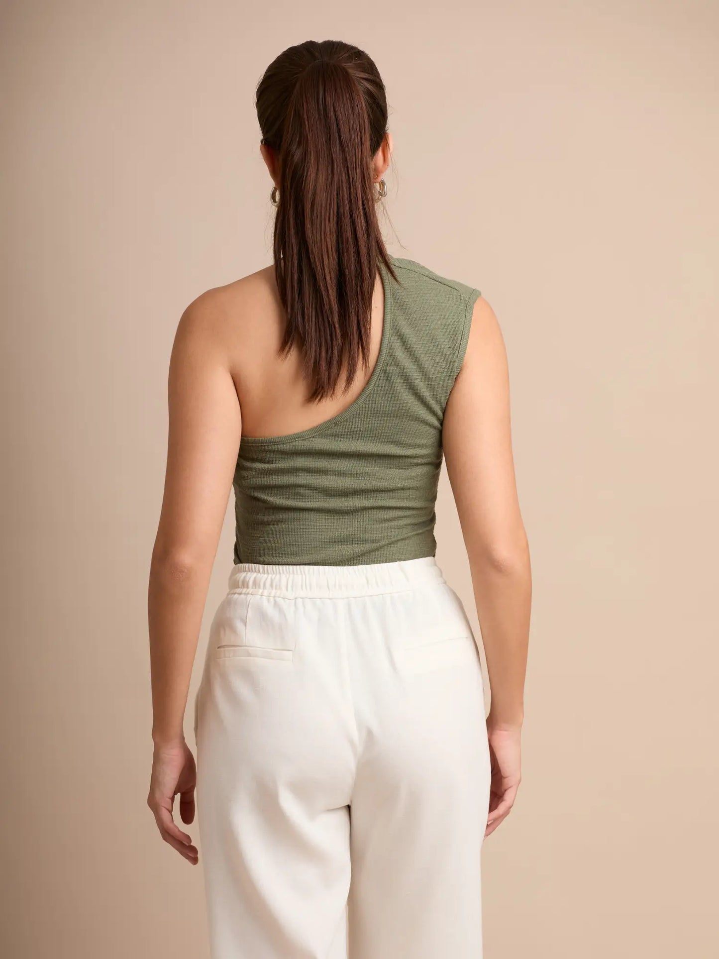 Este top ajustado resalta tu silueta gracias a su diseño asimétrico y tirante con aro metálico. Perfecto para combinar con prendas casuales o elevar un outfit de noche con un toque sofisticado.