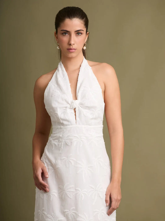 Una pieza femenina y elegante con textura bordada inspirada en palmeras. Su escote halter con nudo y silueta recta crean un look estilizado y atemporal.