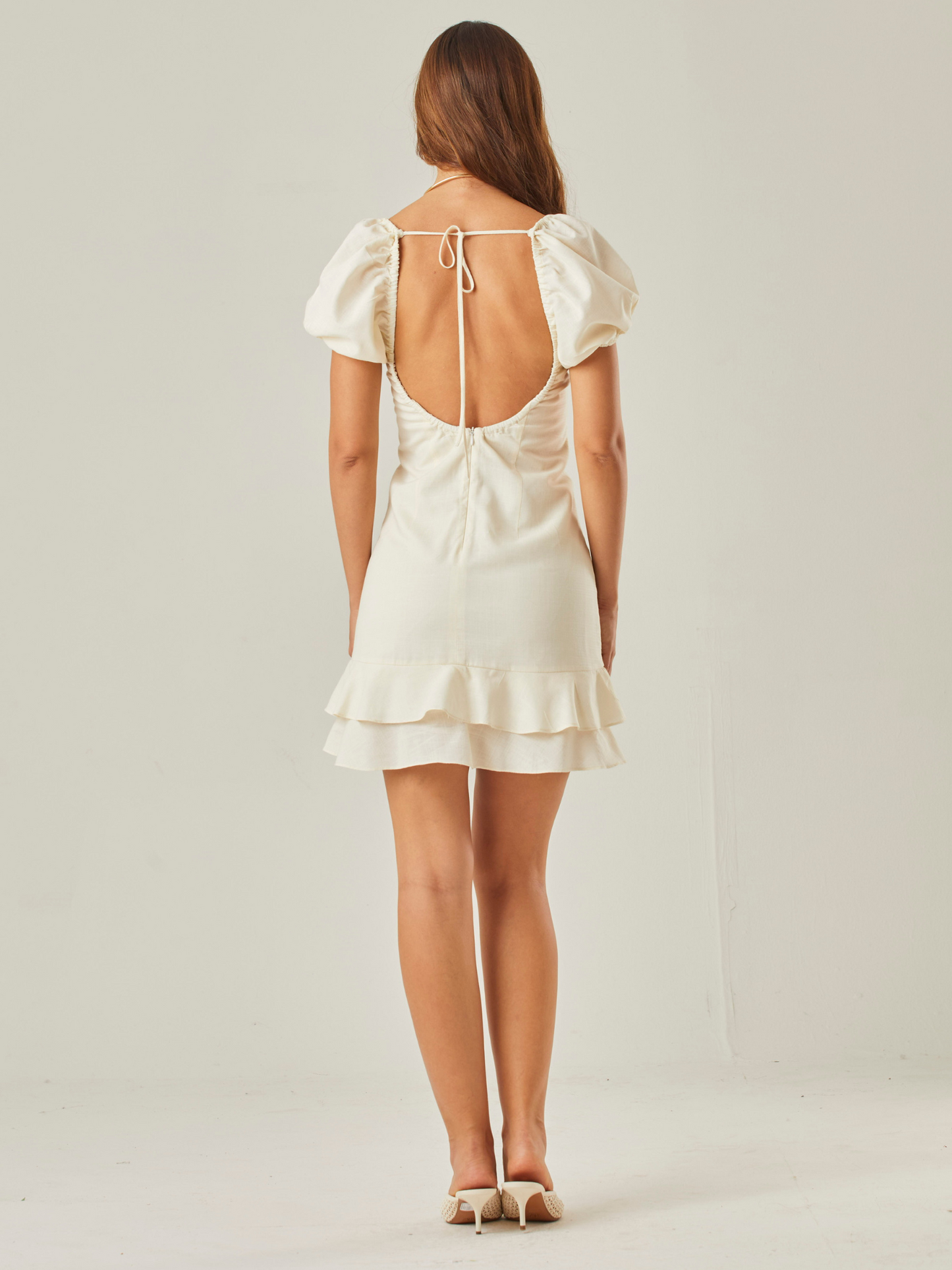 Vestido corto  con  diseño romántico y femenino. Tiene  mangas cortas abullonadas que añaden un toque delicado, junto con un escote cuadrado y detalle fruncido con lazo en el centro, que realza el busto de manera sutil. Su silueta entallada estiliza la figura, mientras que el doble volante en el bajo aporta movimiento y un aire sofisticado. Perfecto para ocasiones especiales o un look casual elegante.