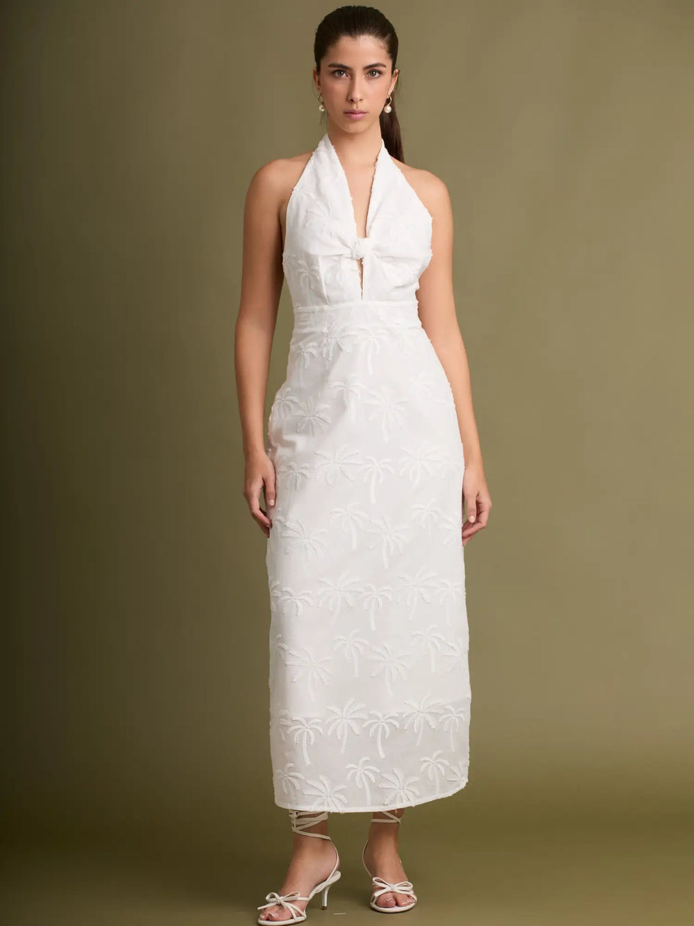 Este vestido halter en tono blanco destaca por su delicado bordado de palmeras y su elegante nudo frontal. Un diseño fresco y sofisticado ideal para días especiales o eventos al aire libre.