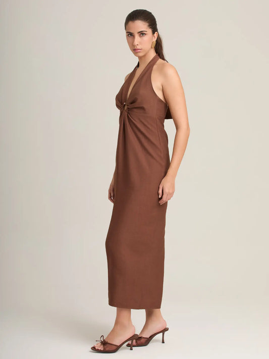 El vestido halter café presenta un nudo central que estiliza la figura y una falda recta midi que alarga visualmente. Una pieza perfecta para ocasiones de día o noche.