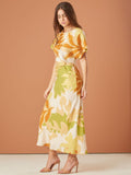 Vestido largo con estampado tropical en tonos cálidos, tiene mangas cortas, un diseño de nudo en la cintura que resalta la figura, y está confeccionado en una tela ligera, ideal para climas cálidos o eventos casuales.

Detalles: 
Color: Blanco estampado
Material: 90% Rayon y 10% Nylon