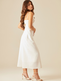 Este vestido tiene un diseño elegante y minimalista. De largo midi y tirantes delgados, destaca por su escote corazón con un pequeño corte central que aporta un toque moderno y sutilmente sensual. La tela estructurada y ligera lo hace ideal para climas cálidos, y combinado con sandalias de tacón y joyería dorada, logra un look sofisticado y femenino.